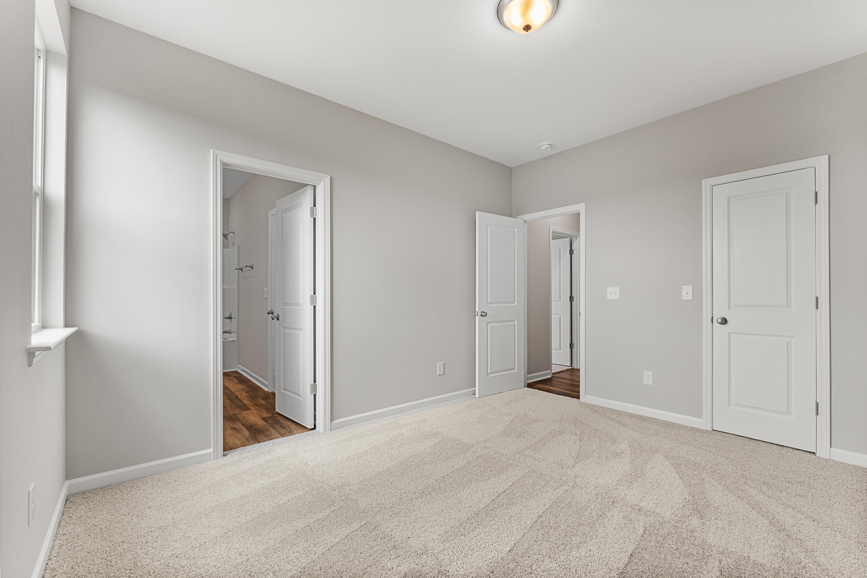 Spacious master bedroom in The Haven E with light gray walls, beige carpet, adjacent bath, and closet doors