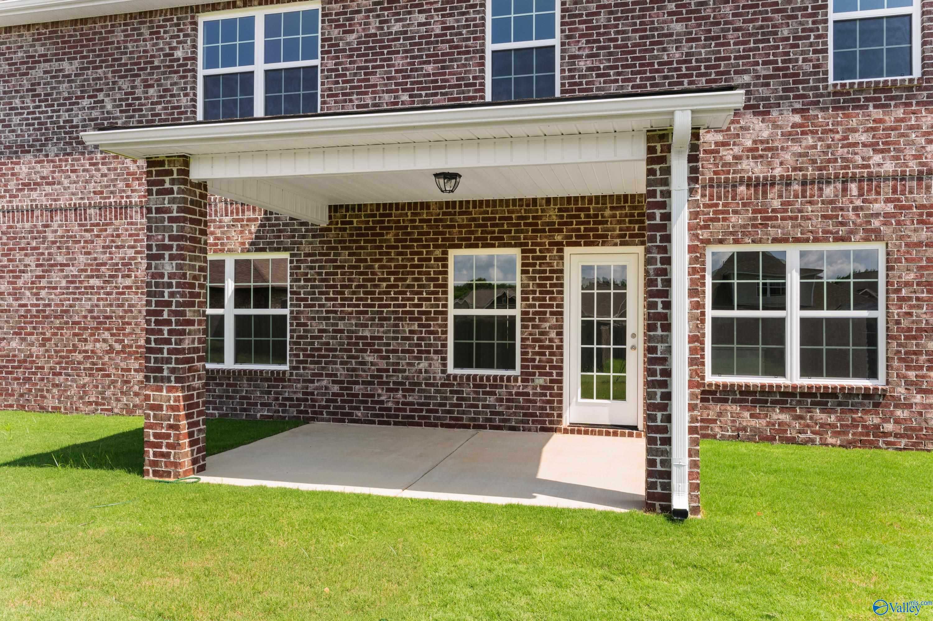 Covered back patio with French doors, brick columns, and lush green yard in Davidson Homes The Madison A, Toney, Alabama