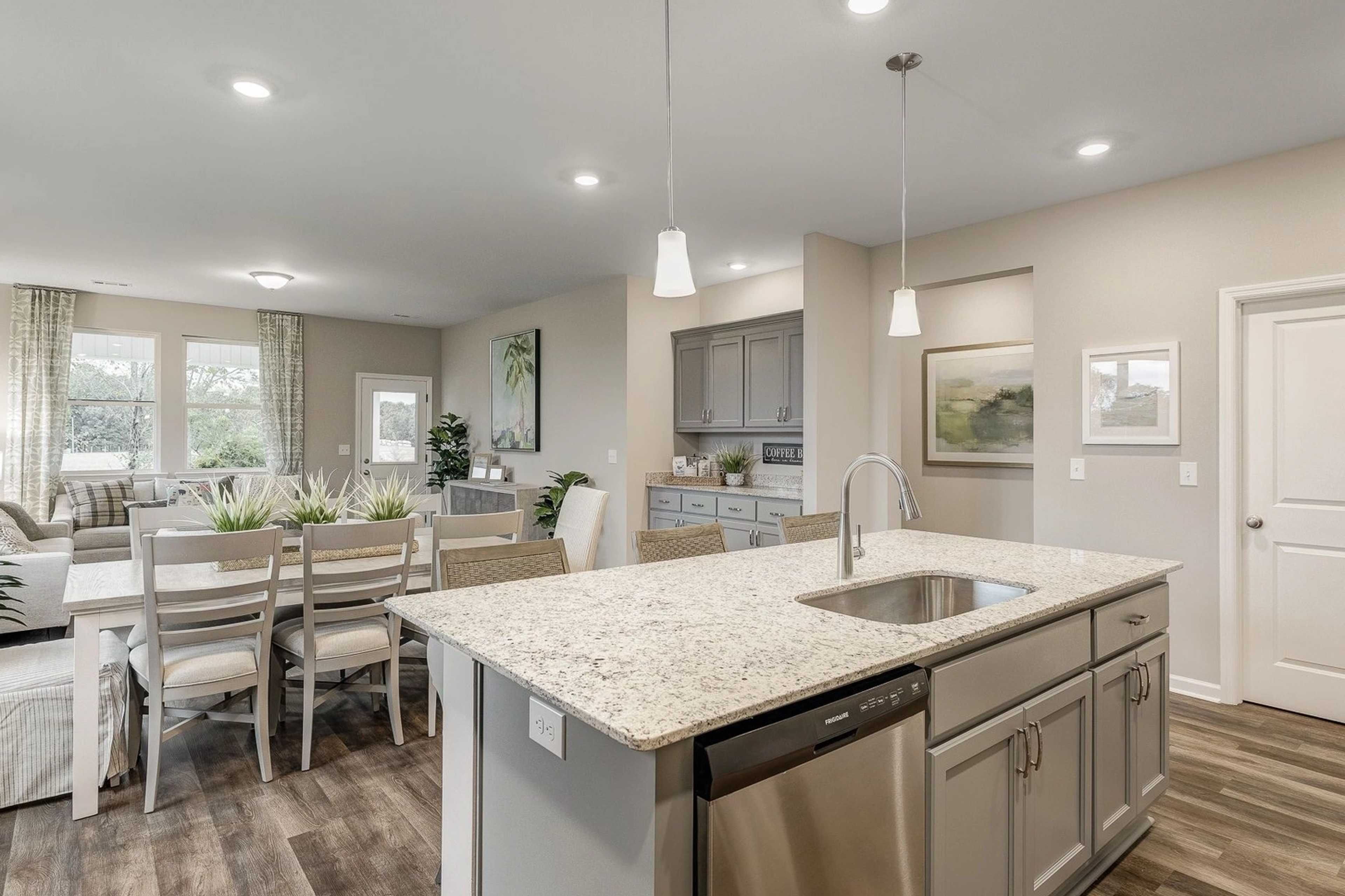 Spacious open-concept kitchen and dining area in Carroll Green, Harvest AL with granite island, hardwood floors, and pendant lights