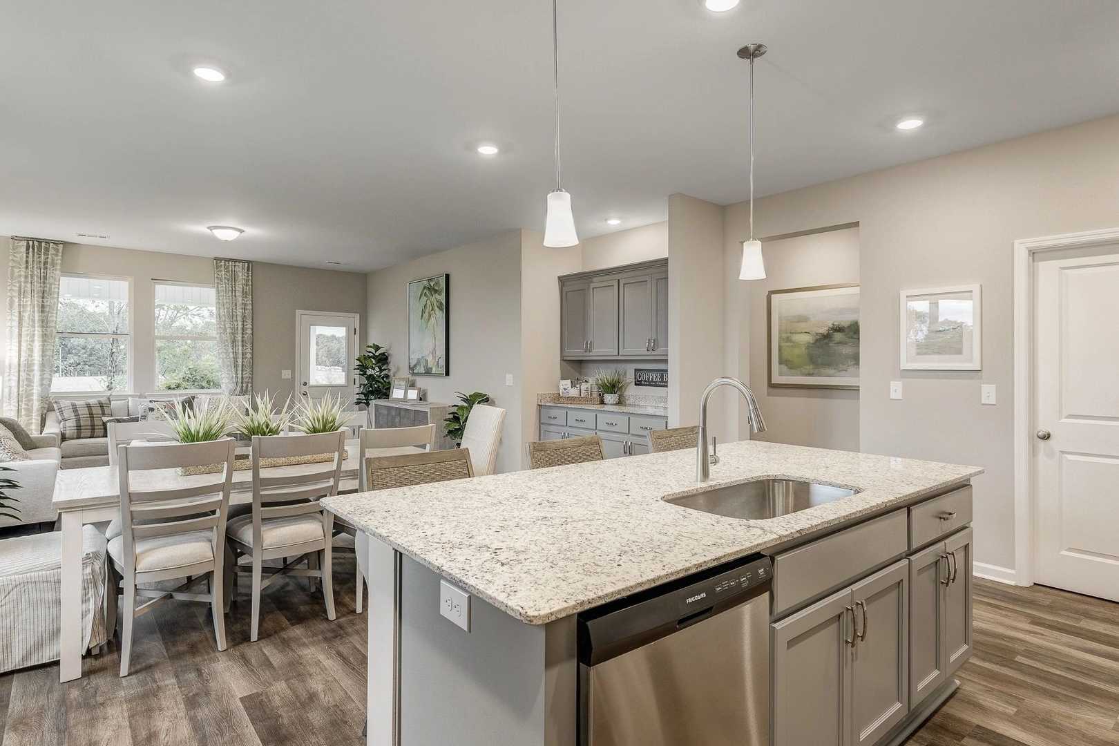 Spacious open-concept kitchen and dining area in Carroll Green, Harvest AL with granite island, hardwood floors, and pendant lights