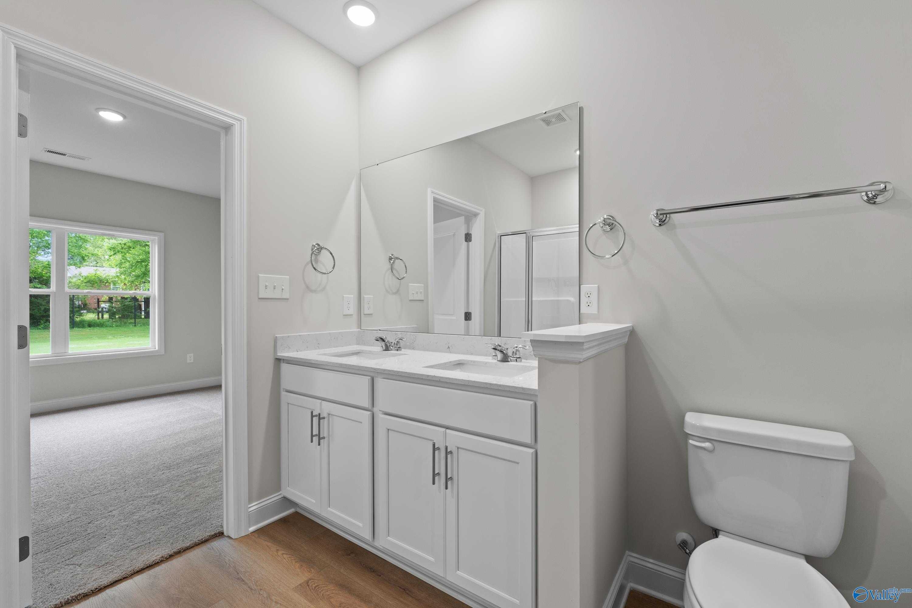 Modern double vanity bathroom with white cabinets, large mirror, and walk-in shower in Davidson Homes The Asheville C, Huntsville