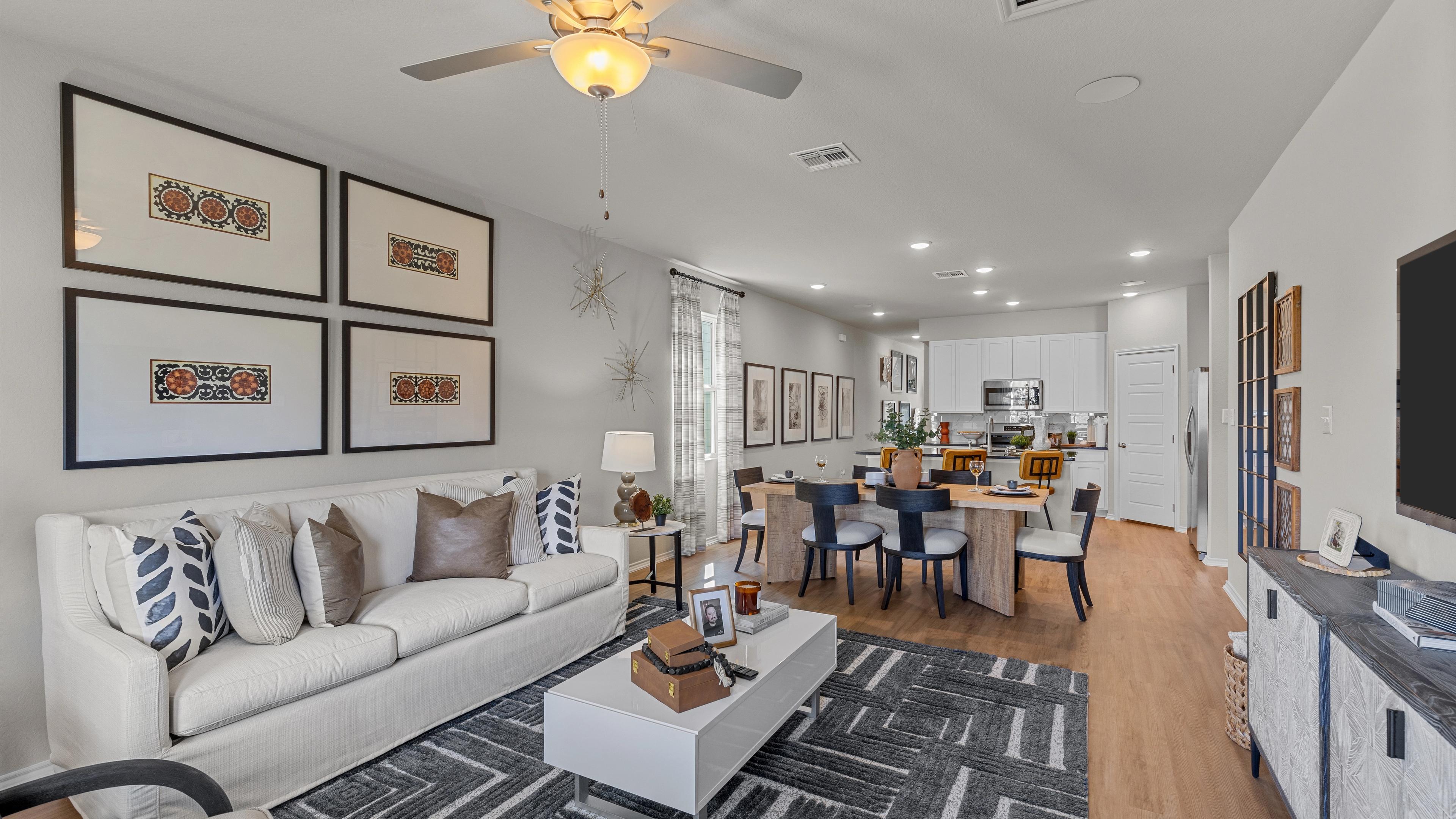 Spacious open-concept living room at Applewhite Meadows San Antonio TX with white sofa, dining table, hardwood floors, and modern wall art