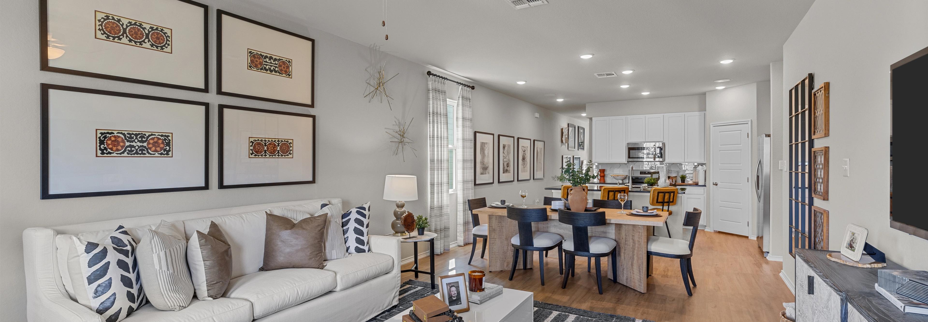 Spacious open-concept living room at Applewhite Meadows San Antonio TX with white sofa, dining table, hardwood floors, and modern wall art