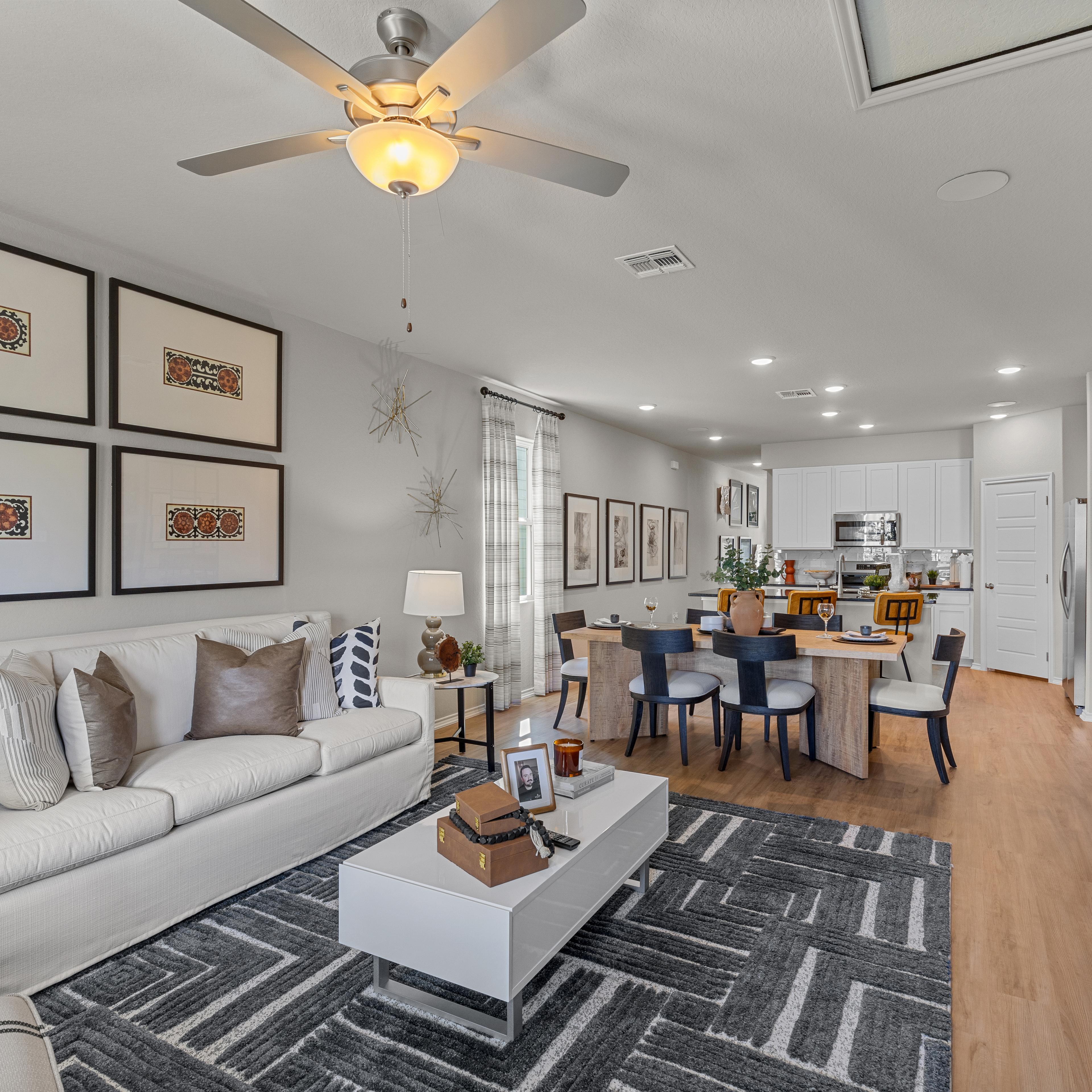 Spacious open-concept living room at Applewhite Meadows San Antonio TX with white sofa, dining table, hardwood floors, and modern wall art