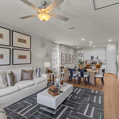 Spacious open-concept living room at Applewhite Meadows San Antonio TX with white sofa, dining table, hardwood floors, and modern wall art