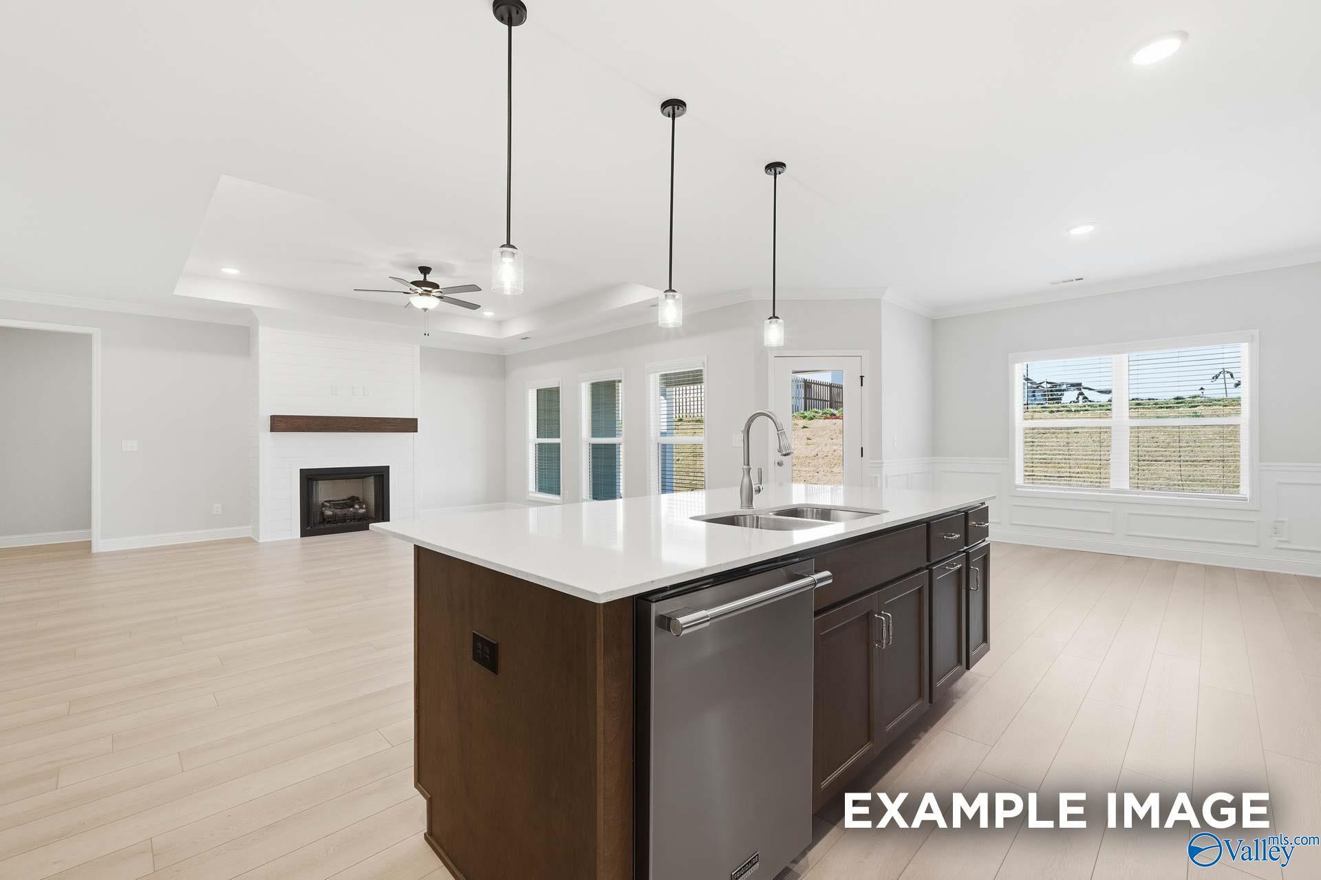 Open-concept kitchen with island and pendant lights overlooking fireplace in Davidson Homes The Harrison D, Madison, Alabama