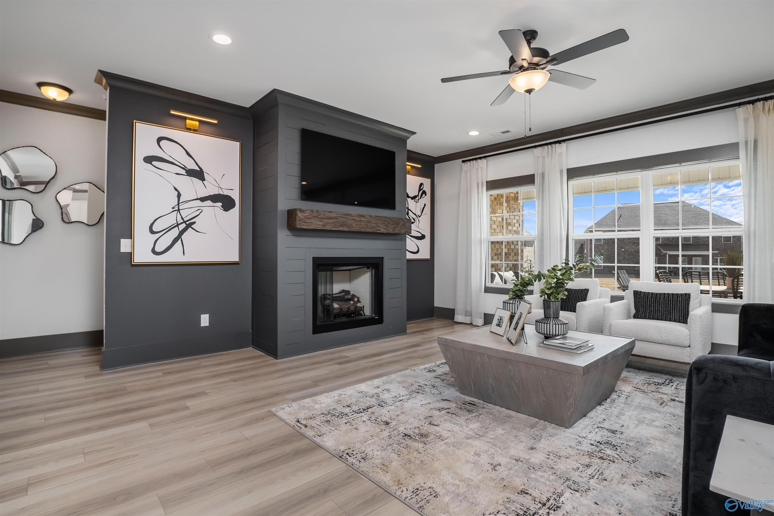 Cozy living room with gas fireplace, mounted TV, modern abstract art, and large windows in Davidson Homes The Rockford B, Madison, Alabama