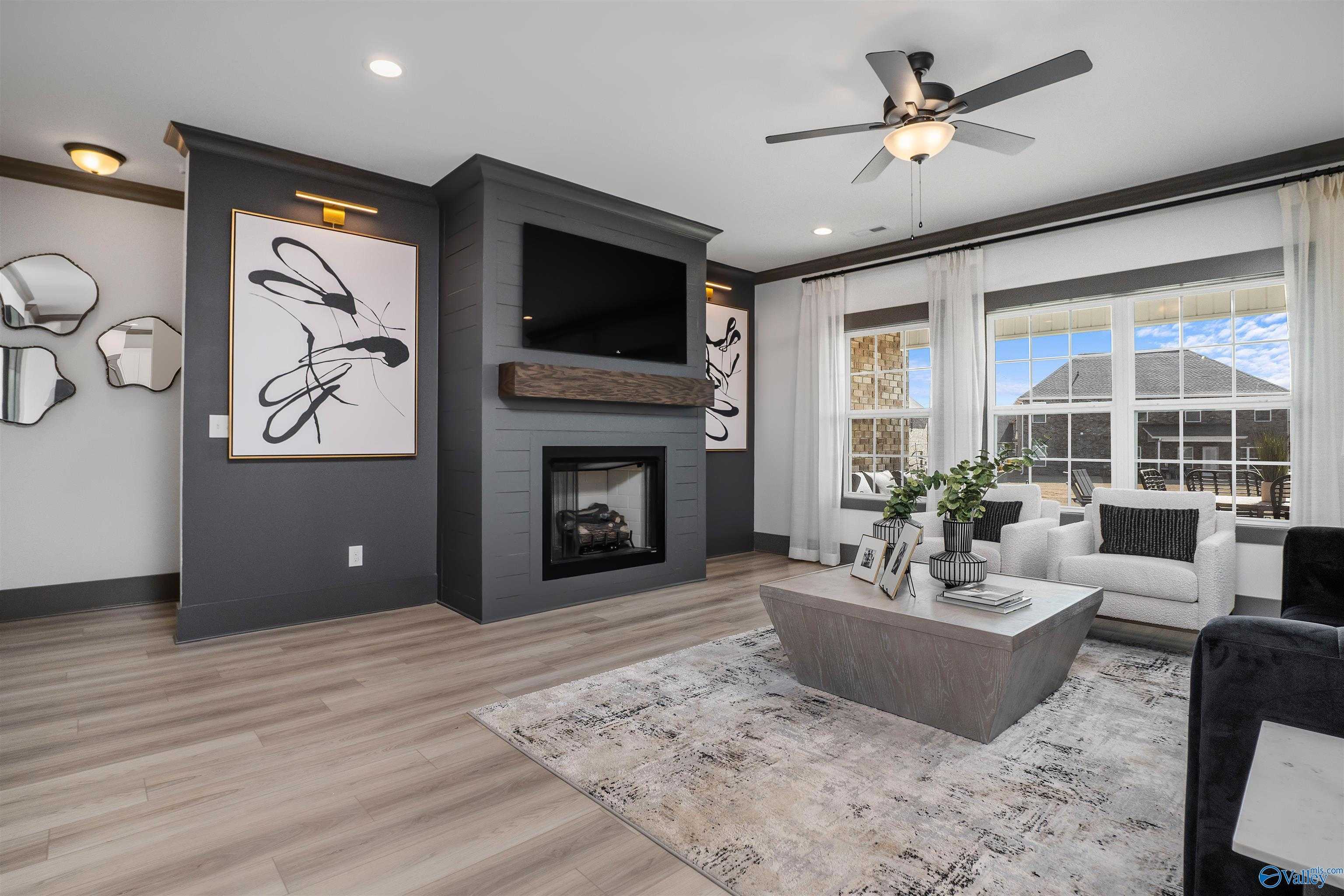 Cozy living room with gas fireplace, mounted TV, modern abstract art, and large windows in Davidson Homes The Rockford B, Madison, Alabama