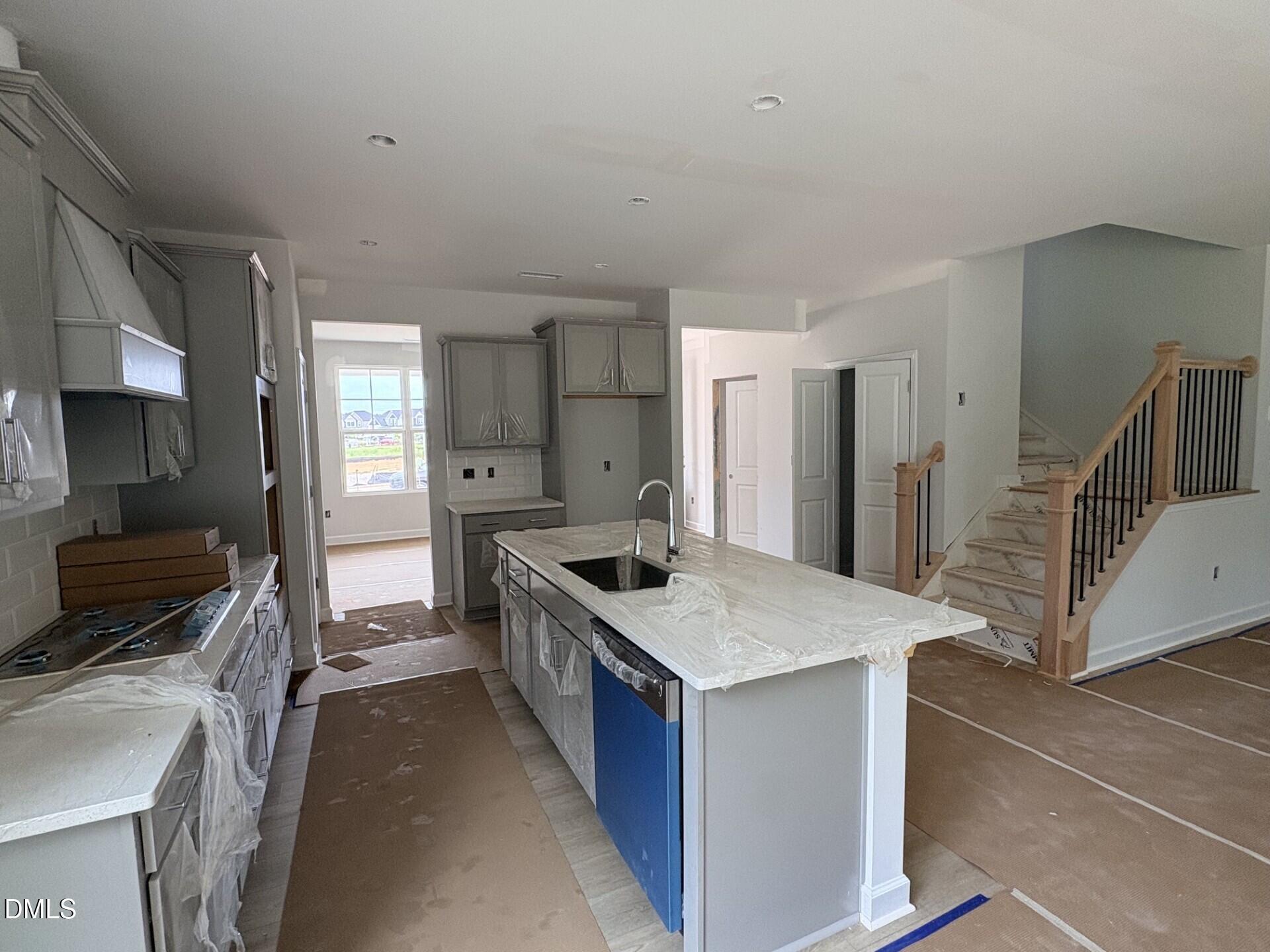 Modern kitchen with center island and staircase under construction in The Ash C floor plan at Woodland Crossing, Zebulon.
