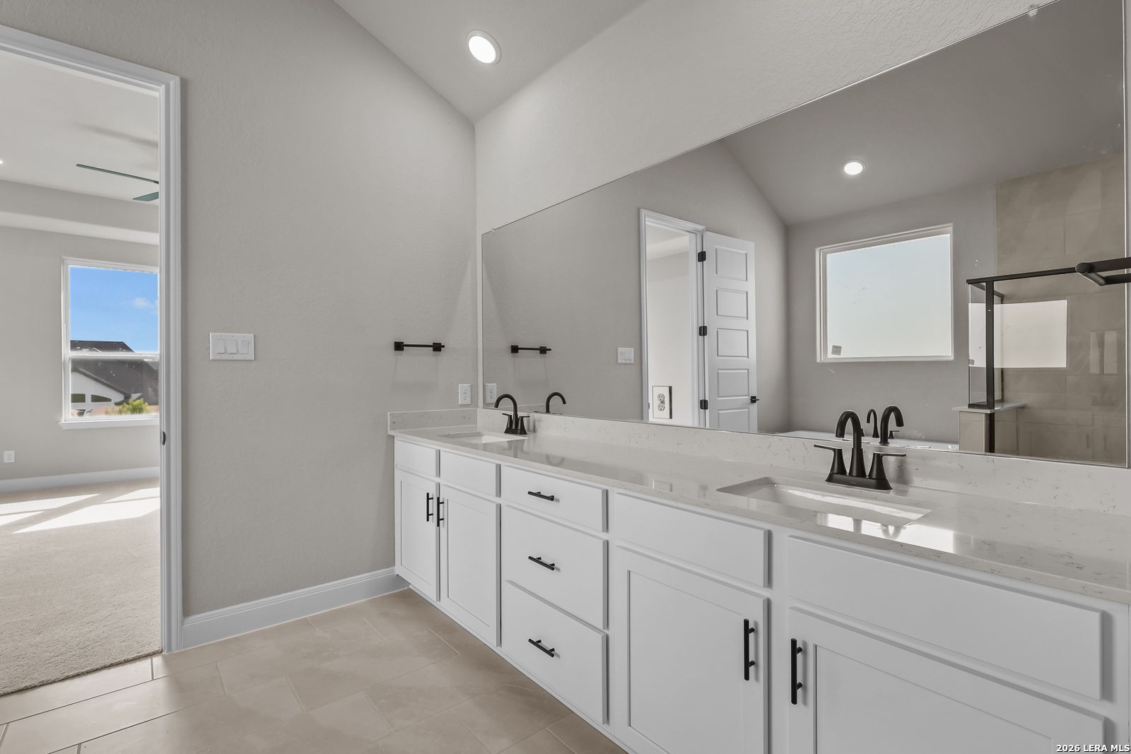 Double vanity bathroom with white cabinets, quartz countertops, and matte black faucets in Davidson Homes Foster E plan, Castroville TX