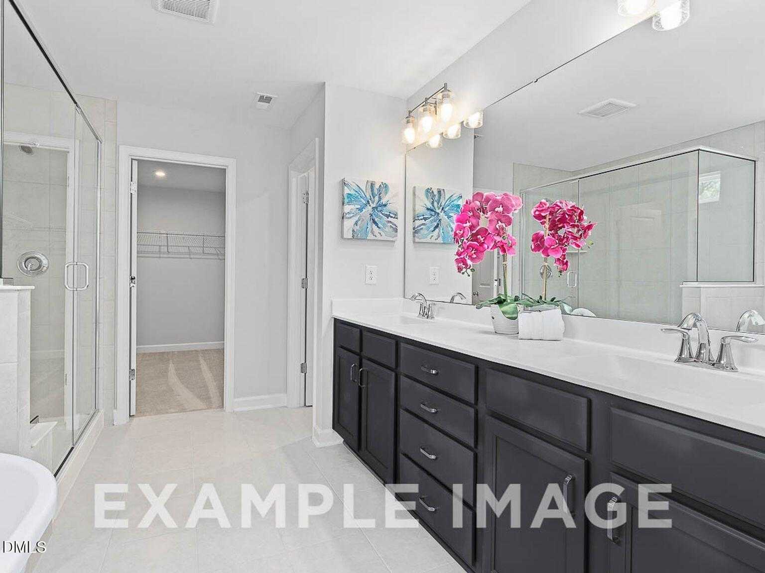 Elegant master bathroom with double black vanity, glass shower, orchids, and walk-in closet in Davidson Homes The Chestnut B, Lillington, NC