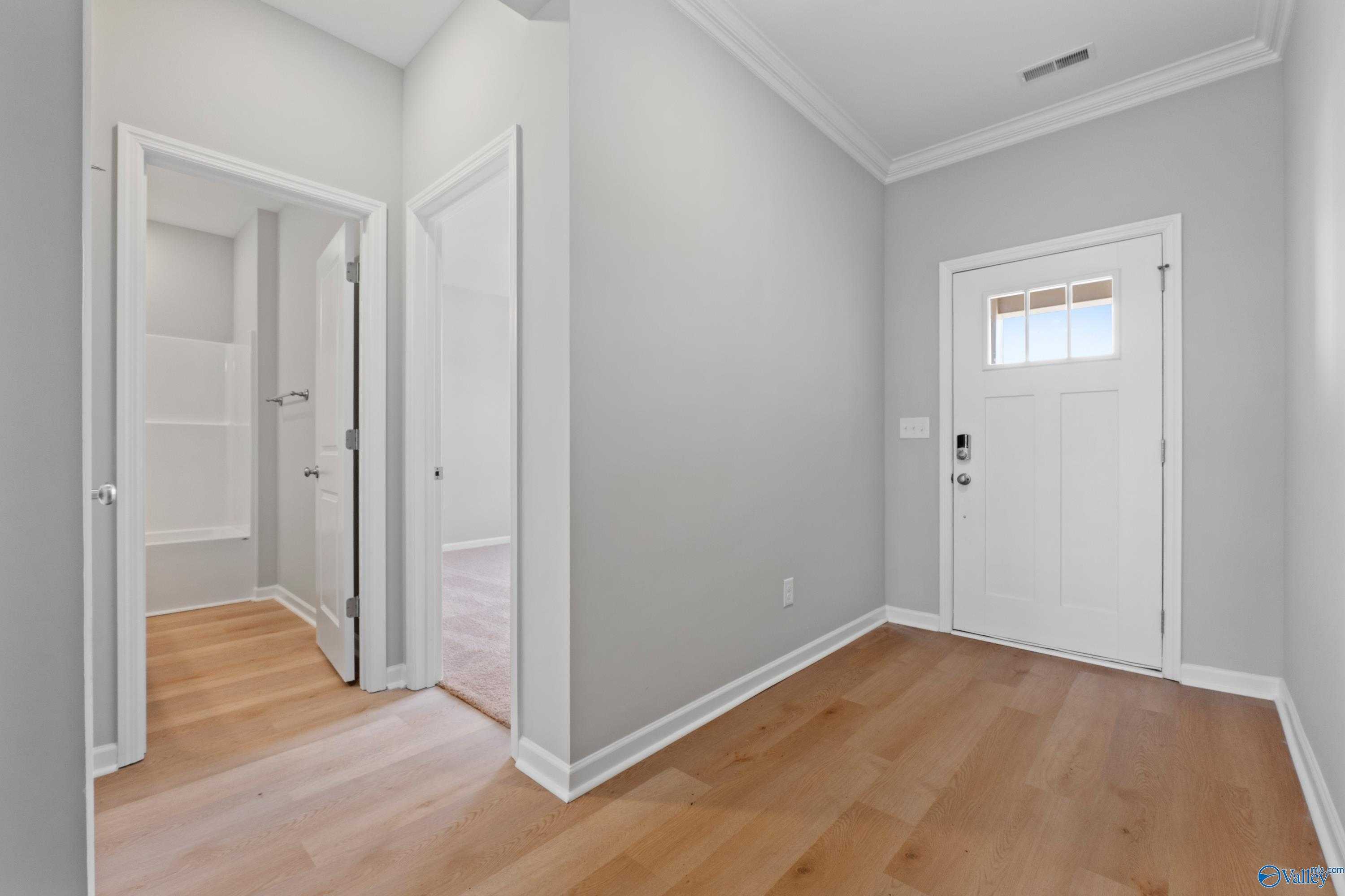 Welcoming entry hallway with gray walls, white doors, and light oak hardwood floors in Davidson Homes The Orion, Athens Alabama