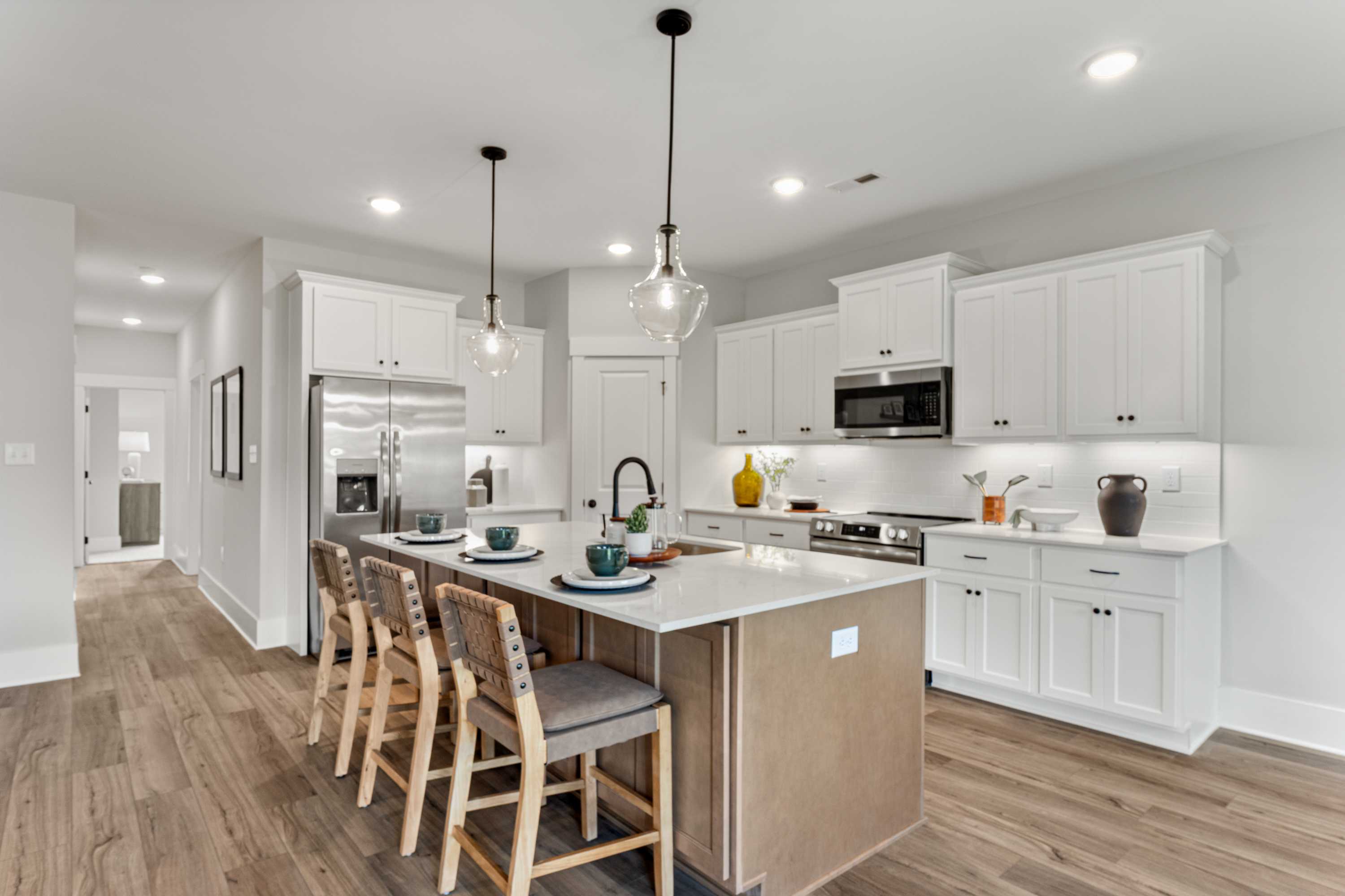 Spacious modern kitchen at River Road Estates in Decatur Alabama with white shaker cabinets, large island, bar seating, and hardwood floors