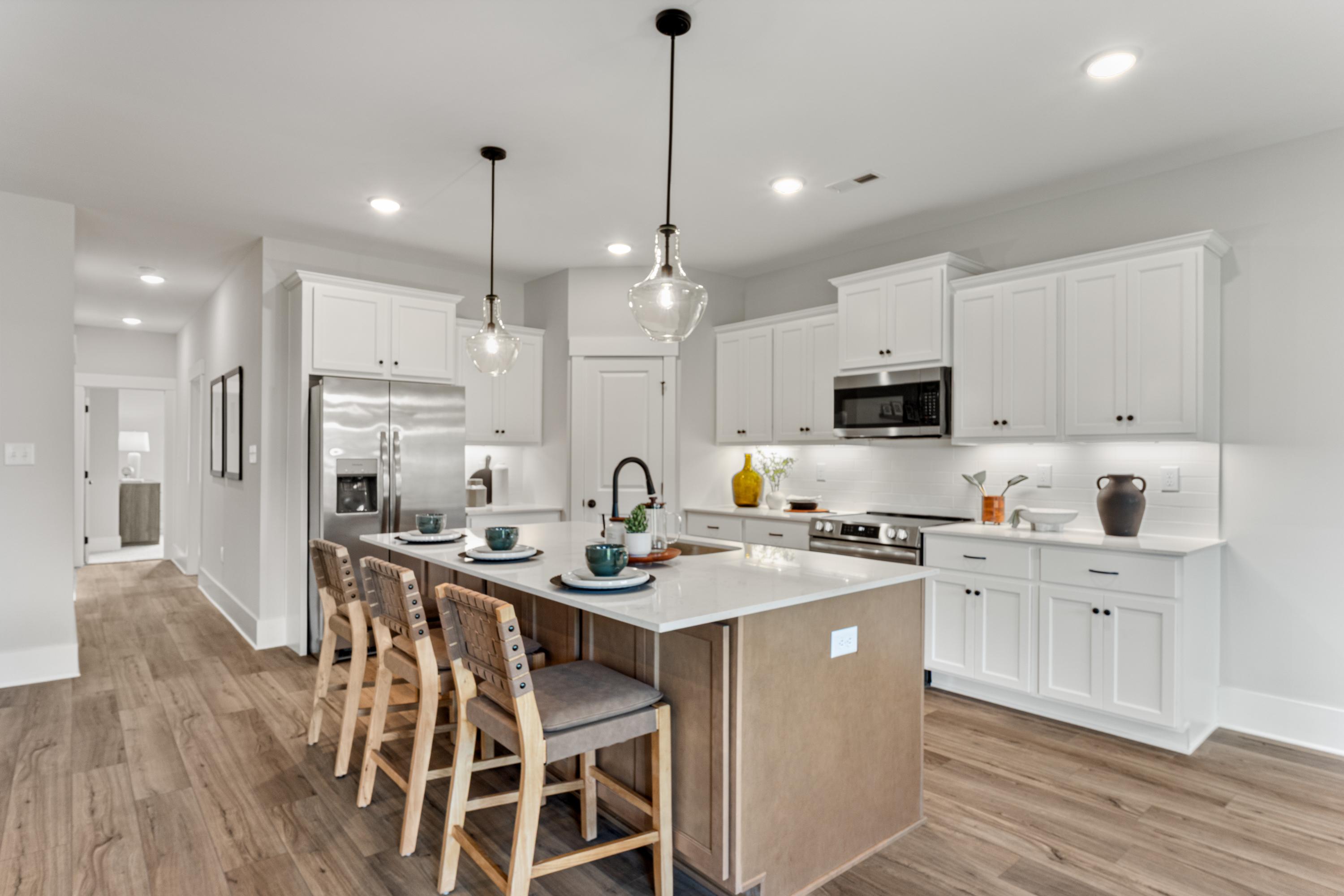Spacious modern kitchen at River Road Estates in Decatur Alabama with white shaker cabinets, large island, bar seating, and hardwood floors