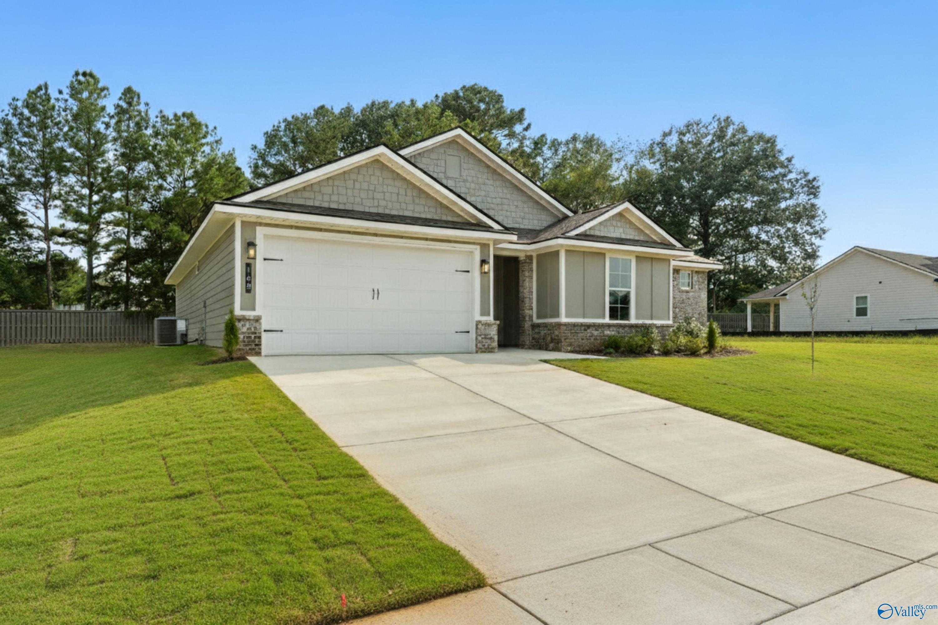 Modern single-story 3-bedroom home with 2-car garage, gray siding, and lush green lawn in Evergreen Mill, Madison, Alabama