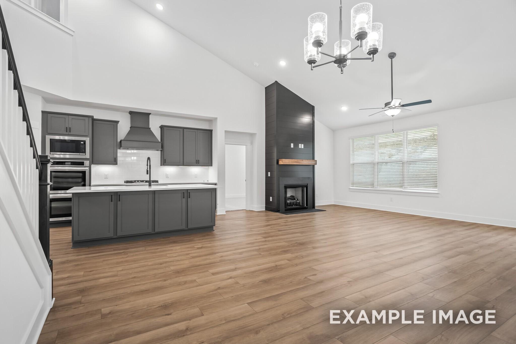 Open-concept kitchen and living room with gray cabinets, stainless appliances, modern fireplace, and high ceilings in Ridgeport C home, Gallatin, TN
