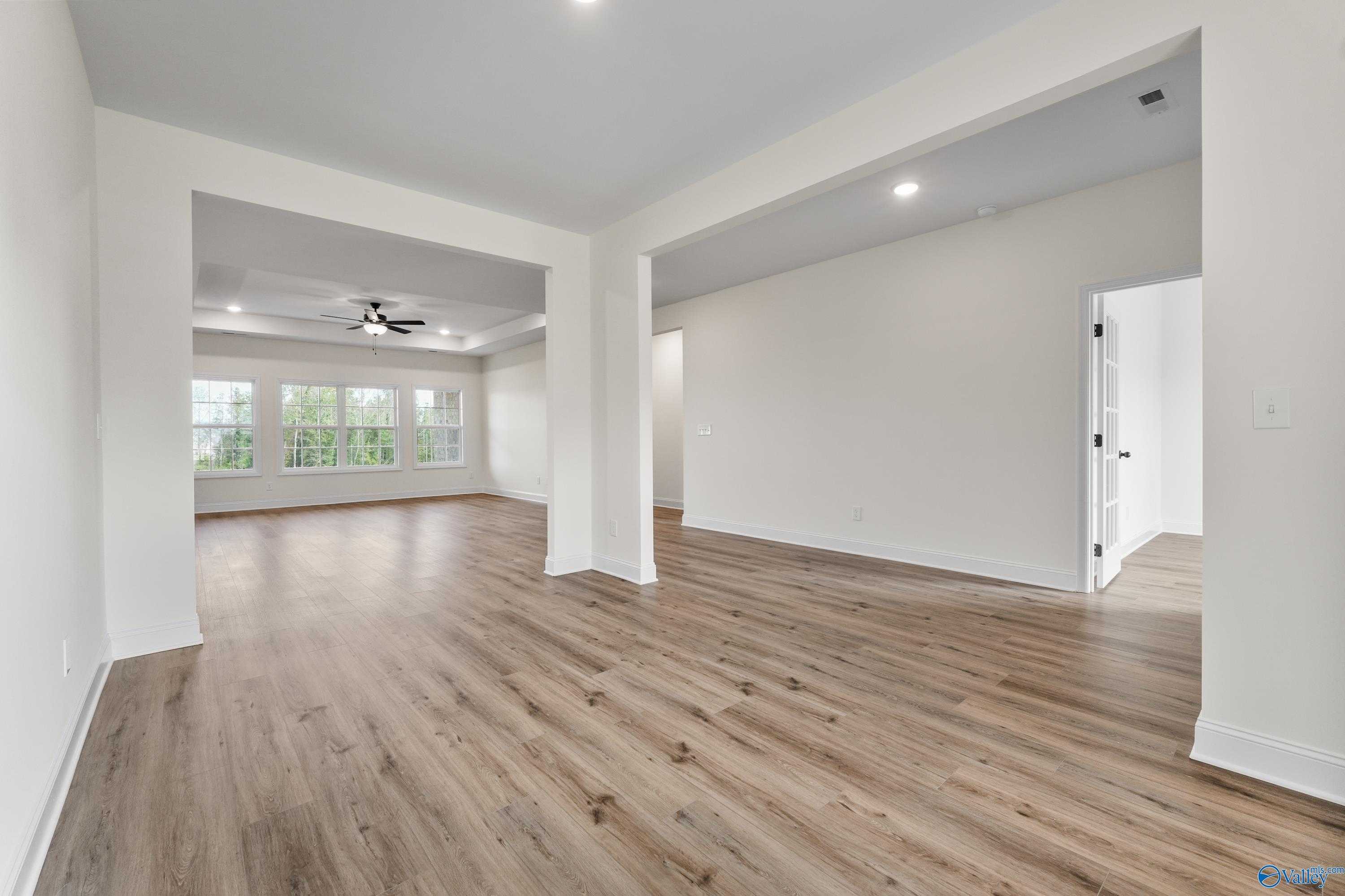 Open living space with hardwood floors, ceiling fan, large windows, and archways in Davidson Homes The Finleigh, Creekside, Harvest, AL
