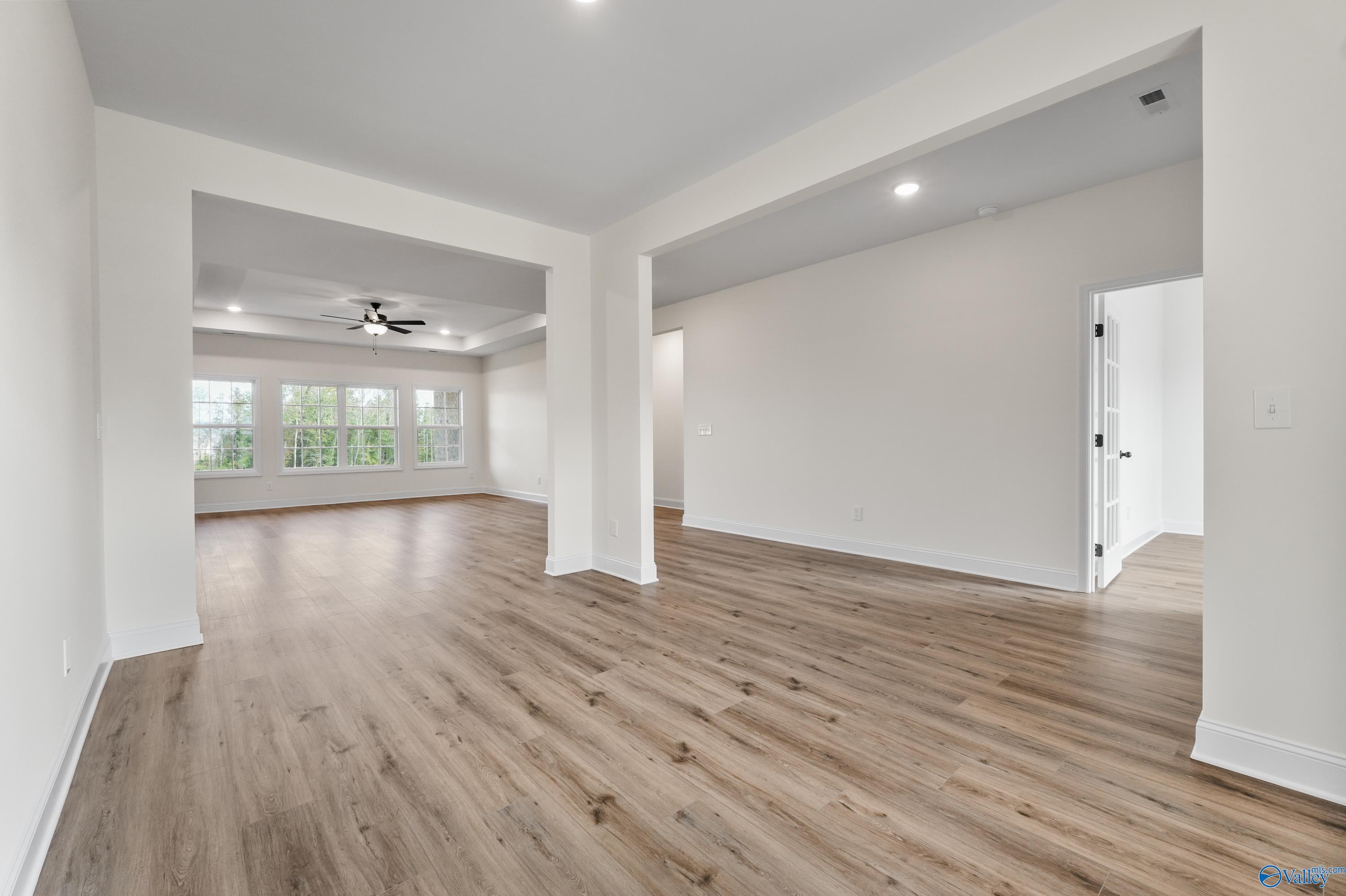 Open living space with hardwood floors, ceiling fan, large windows, and archways in Davidson Homes The Finleigh, Creekside, Harvest, AL