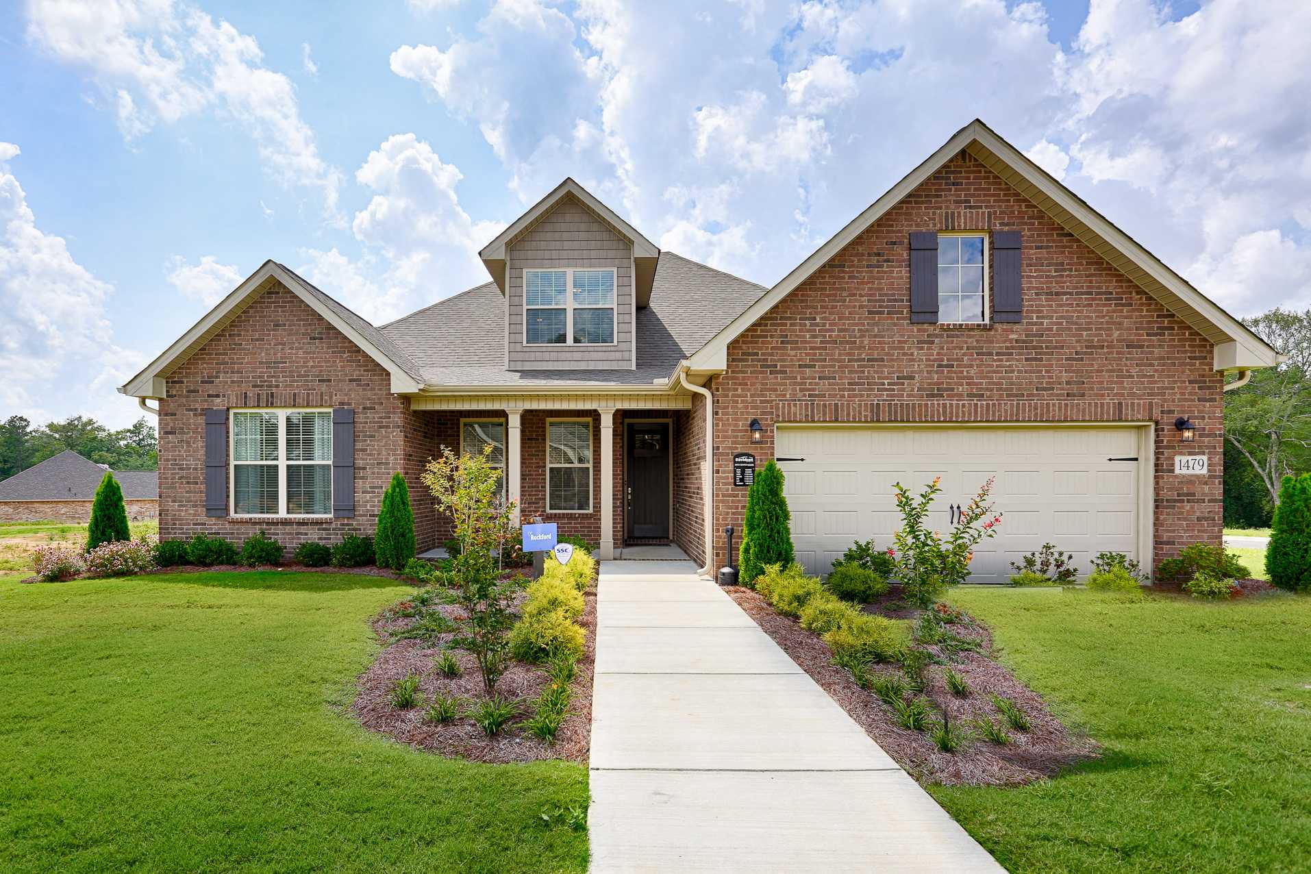 Brick home exterior at Stone Creek Phase II in Cullman Alabama with gabled roof covered porch garage and landscaped yard