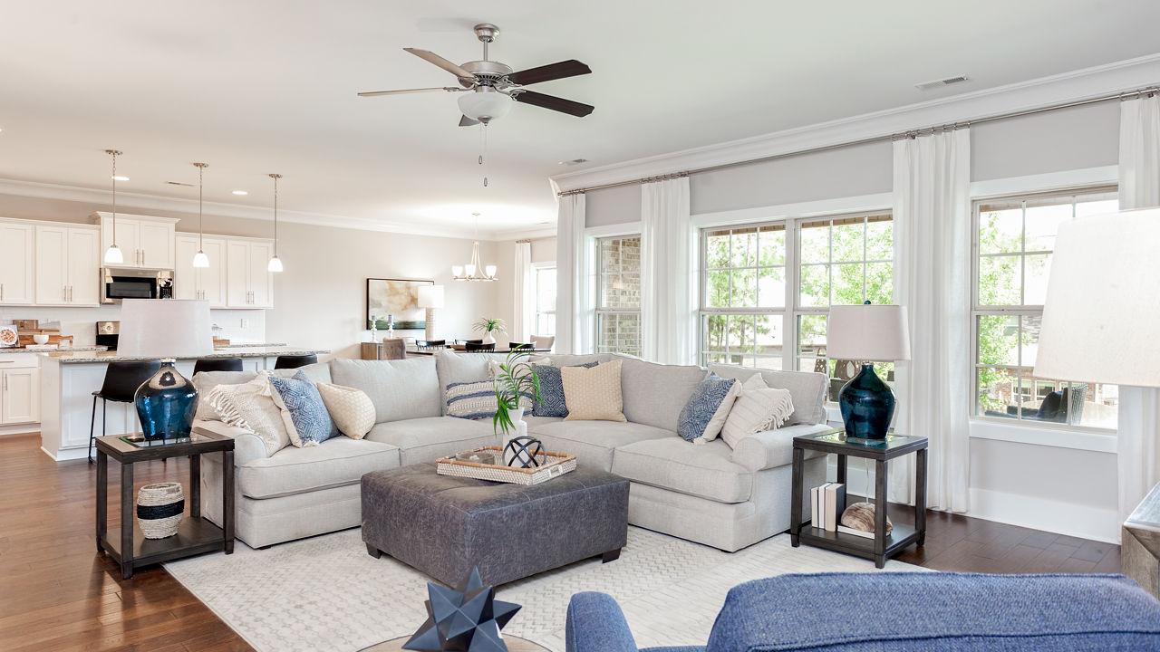 Spacious open-concept living room in Mountain Preserve, Hampton Cove AL by Davidson Homes with L-shaped sofa, hardwood floors, and large windows