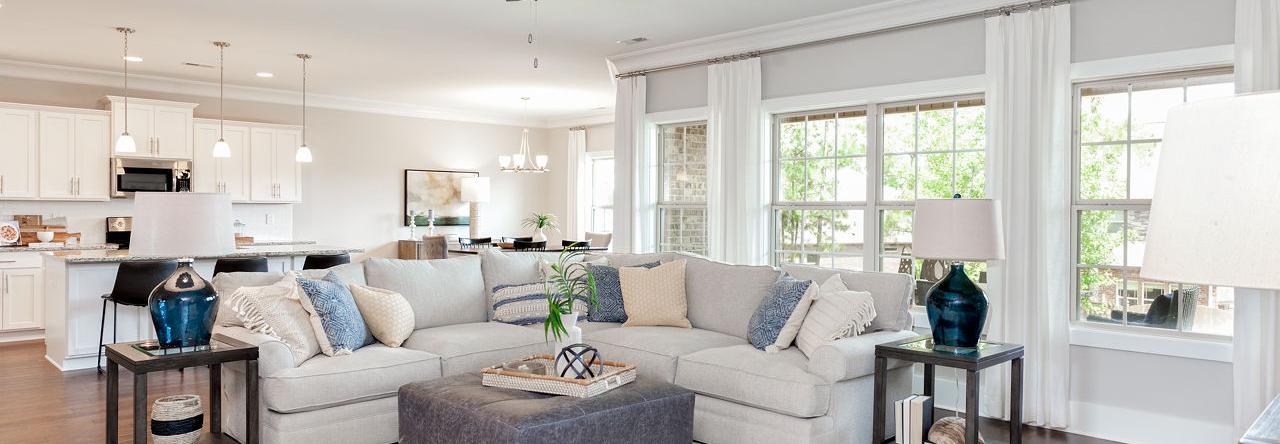 Spacious open-concept living room in Mountain Preserve, Hampton Cove AL by Davidson Homes with L-shaped sofa, hardwood floors, and large windows