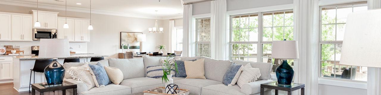 Spacious open-concept living room in Mountain Preserve, Hampton Cove AL by Davidson Homes with L-shaped sofa, hardwood floors, and large windows