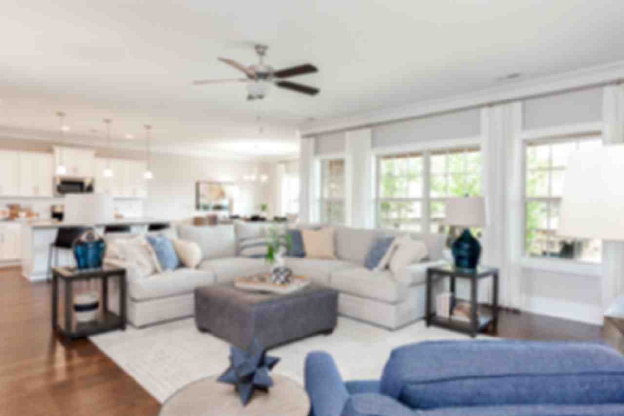 Spacious open-concept living room in Mountain Preserve, Hampton Cove AL by Davidson Homes with L-shaped sofa, hardwood floors, and large windows