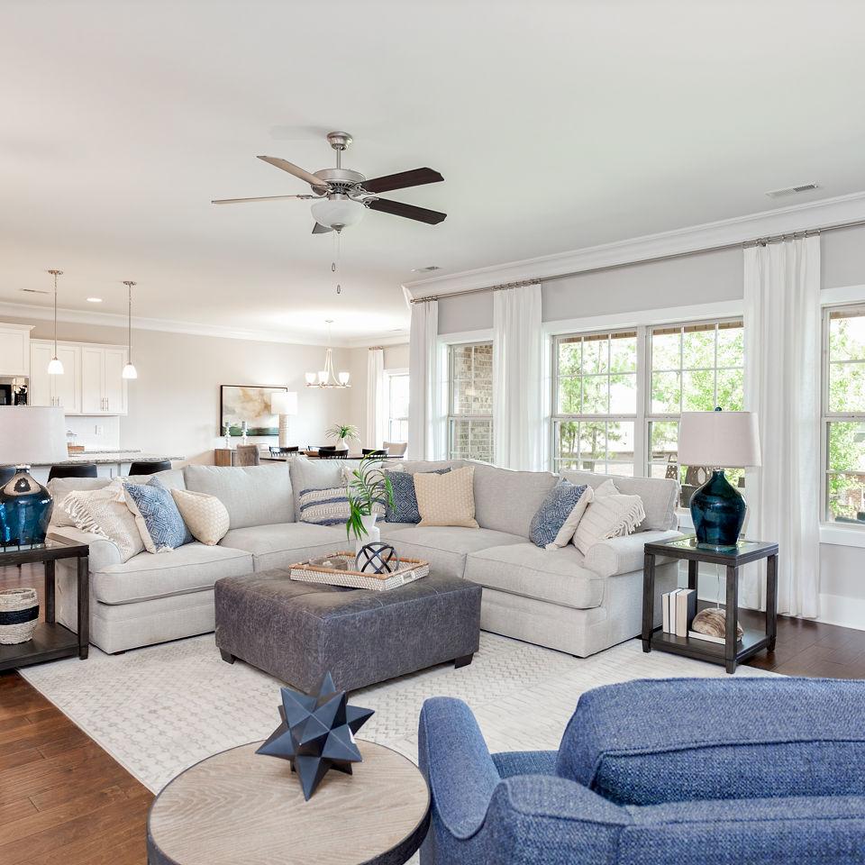 Spacious open-concept living room in Mountain Preserve, Hampton Cove AL by Davidson Homes with L-shaped sofa, hardwood floors, and large windows