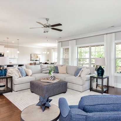 Spacious open-concept living room in Mountain Preserve, Hampton Cove AL by Davidson Homes with L-shaped sofa, hardwood floors, and large windows