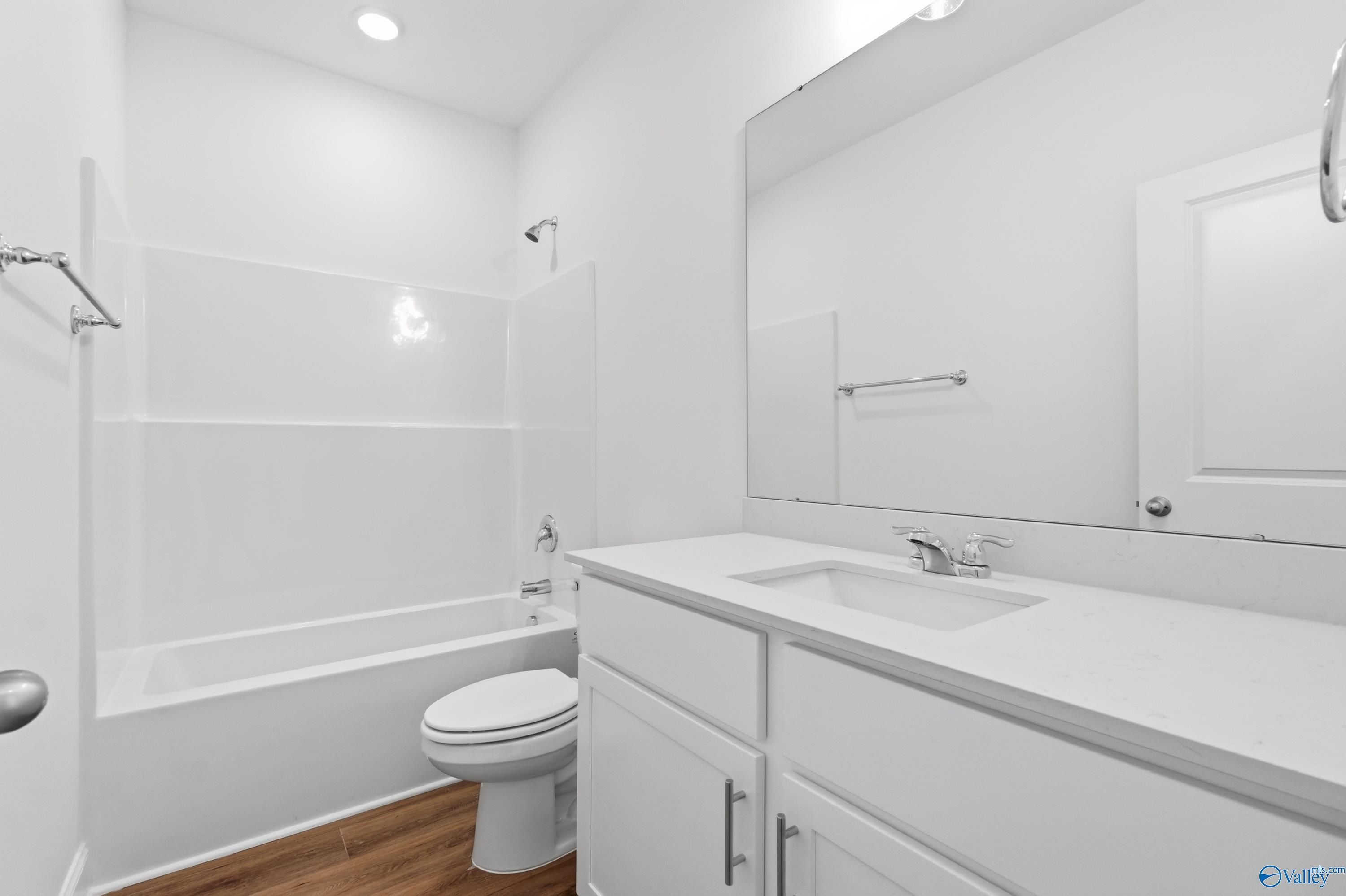 Bright white secondary bathroom with tub-shower combo, single vanity, and toilet in Davidson Homes The Asheville C, Meridianville, AL