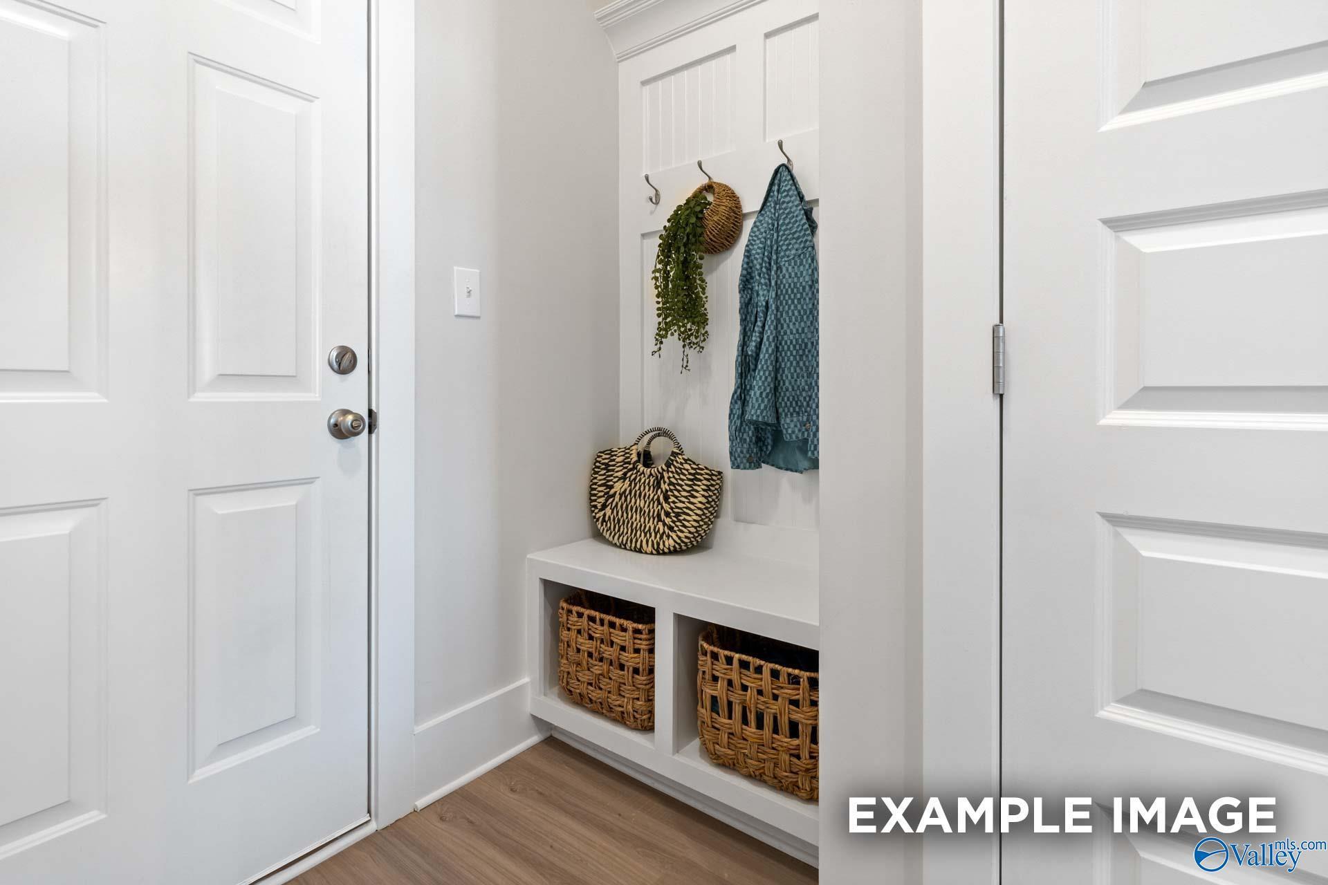White mudroom cubby with bench, coat hooks, and woven storage baskets in Davidson Homes Chelsea A plan, Toney, Alabama