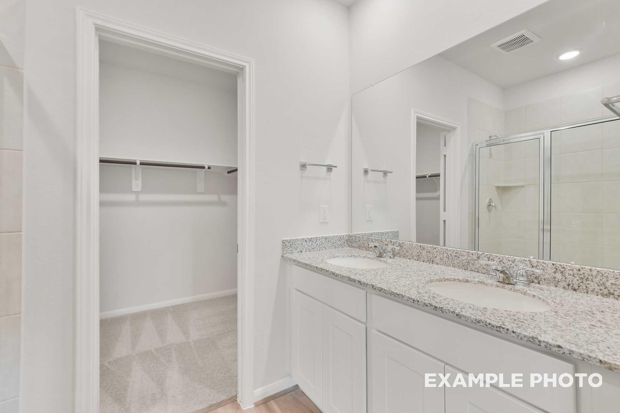 Master bathroom in The Brazos by Davidson Homes featuring dual granite vanities, walk-in shower, and spacious walk-in closet.