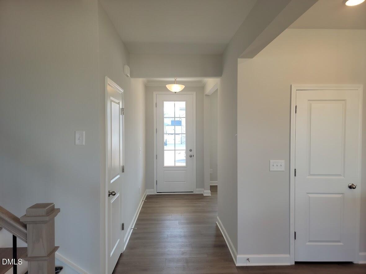 Bright entryway hallway with hardwood floors, white doors, and staircase in 5-bedroom Davidson Homes The Willow G, Angier, NC