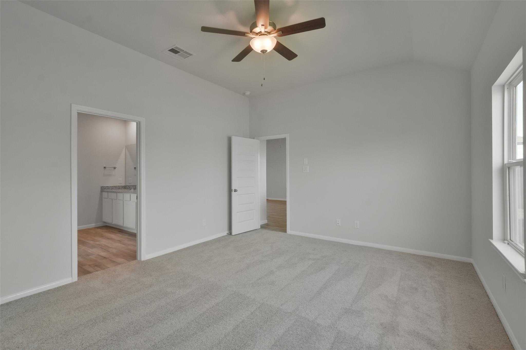Spacious master bedroom with ceiling fan, en-suite bath, and walk-in closet in Davidson Homes The Tierra A, Dayton, Texas