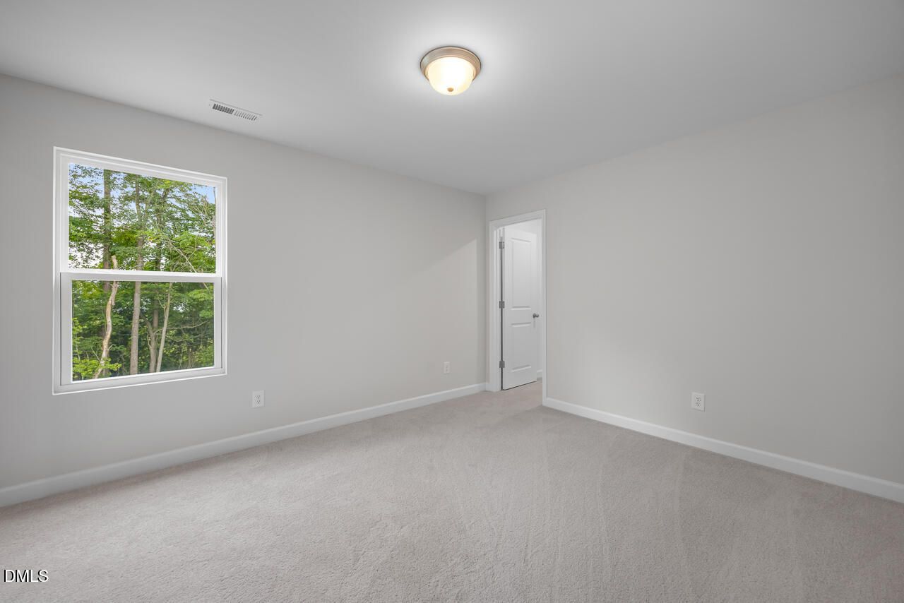 Bright, neutral-colored bedroom in The Hickory II B floor plan by Davidson Homes in Wellers Knoll, Lillington, NC.