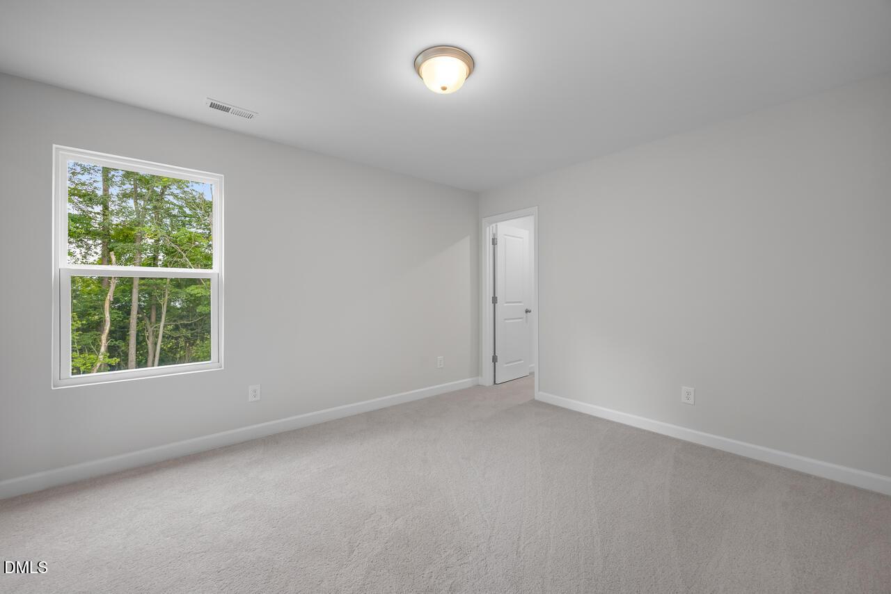 Bright, neutral-colored bedroom in The Hickory II B floor plan by Davidson Homes in Wellers Knoll, Lillington, NC.