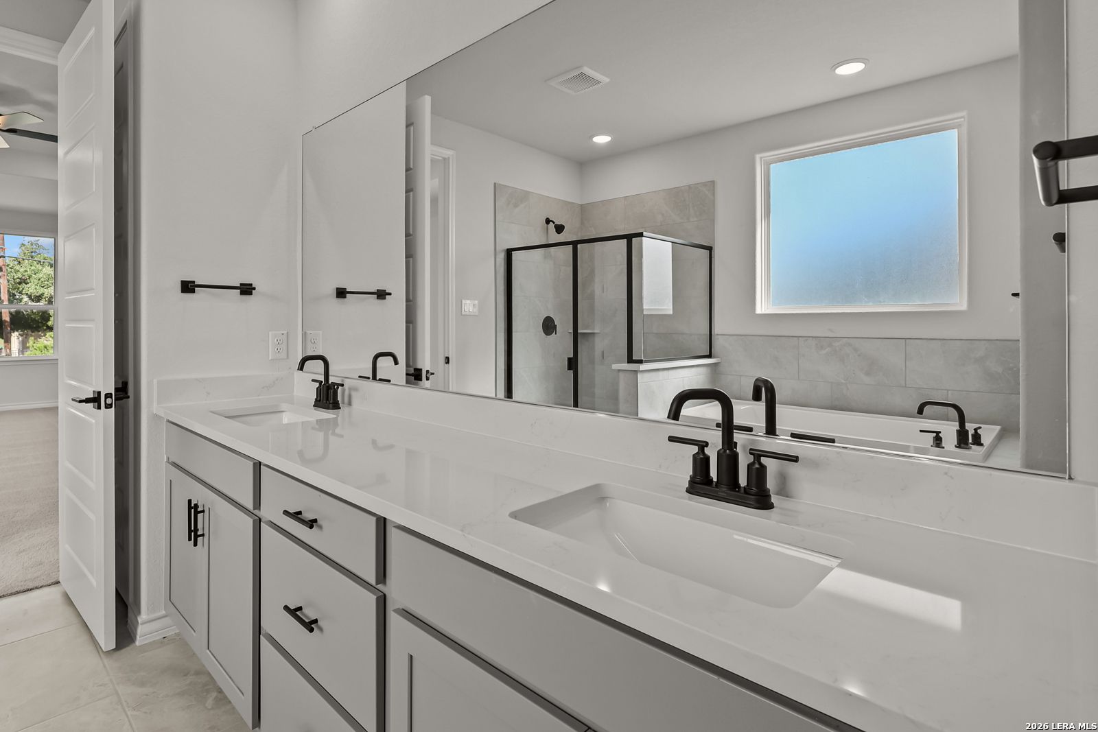 Double vanity bathroom with white quartz countertops, matte black fixtures, and glass shower in Davidson Homes Oxford F plan, Castroville TX