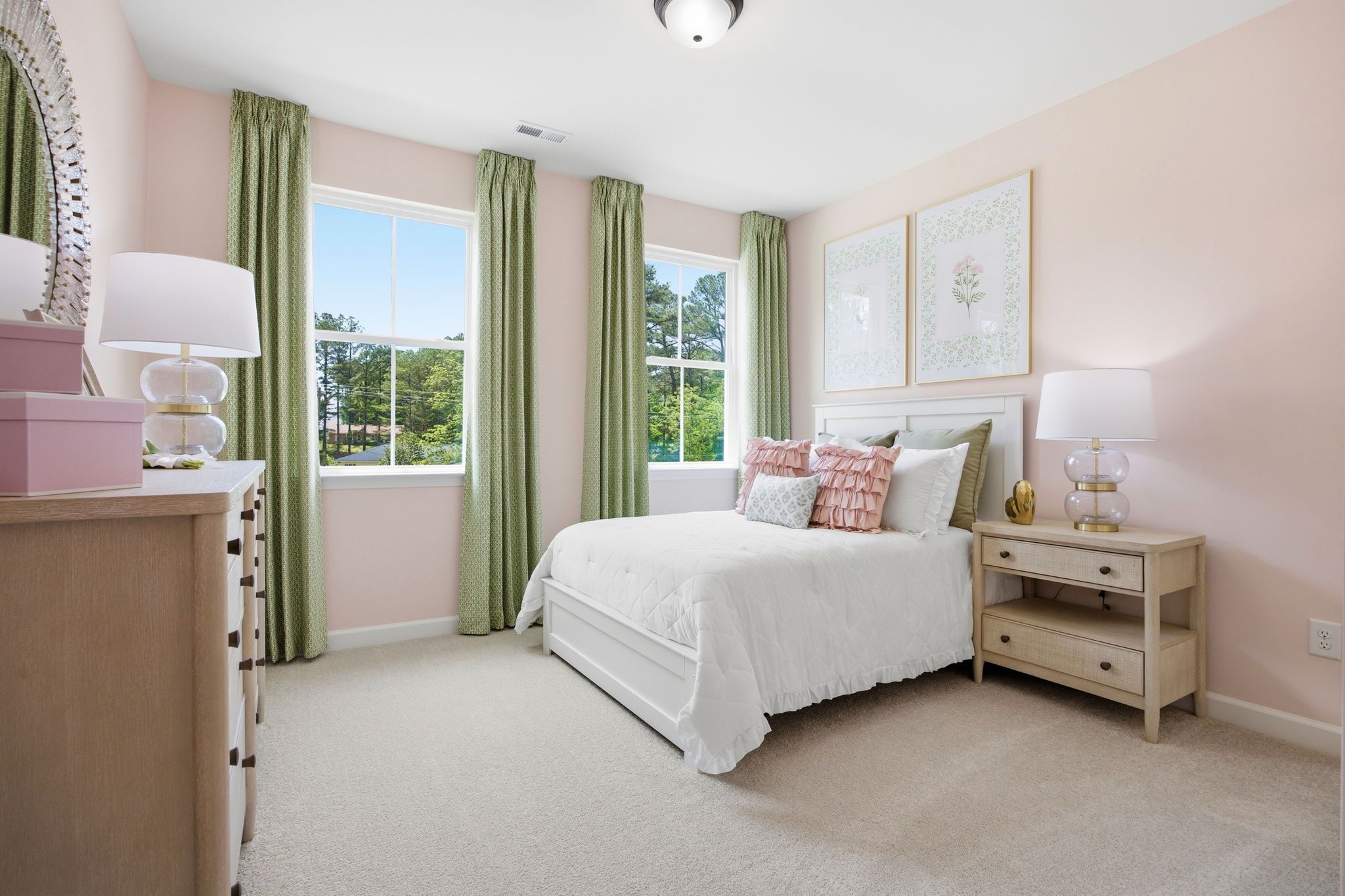 Bright, airy bedroom in The Ashport featuring soft pink walls, white bedding, green curtains, and natural light.
