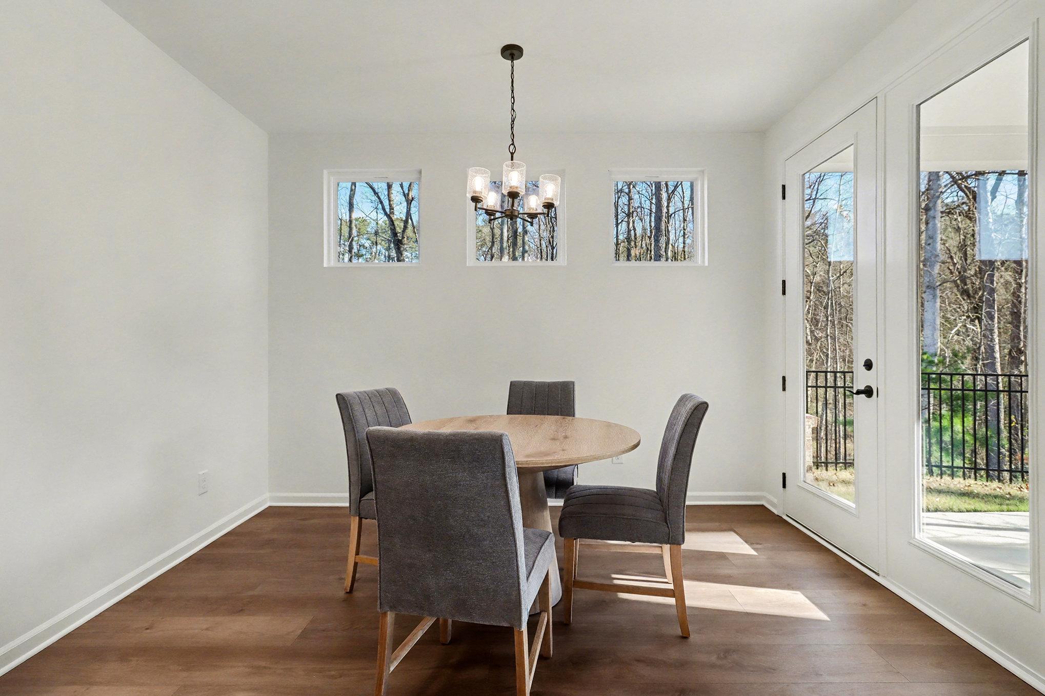 Open-concept dining room with round dining table, and hardwood floors in Davidson Homes The Daphne B, Loganville, GA