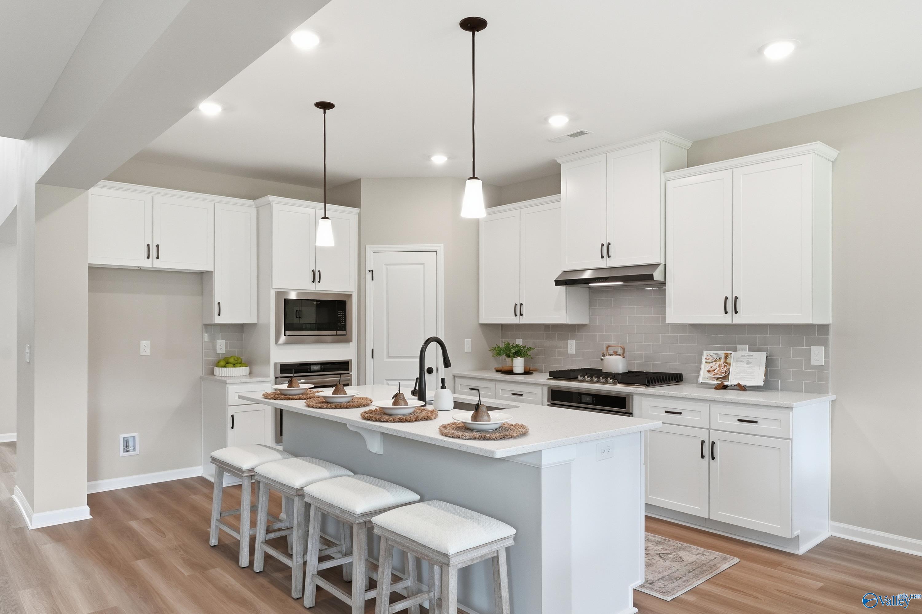 Modern white kitchen with quartz island, stainless gas range, subway tile backsplash in Davidson Homes The Dorado, Huntsville AL