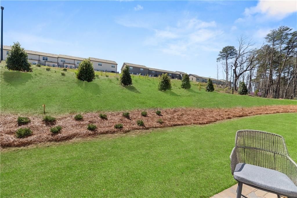 Inviting gray wicker chair on patio overlooking lush green lawn, pine trees, and modern homes in The Bluffs, Canton, Georgia
