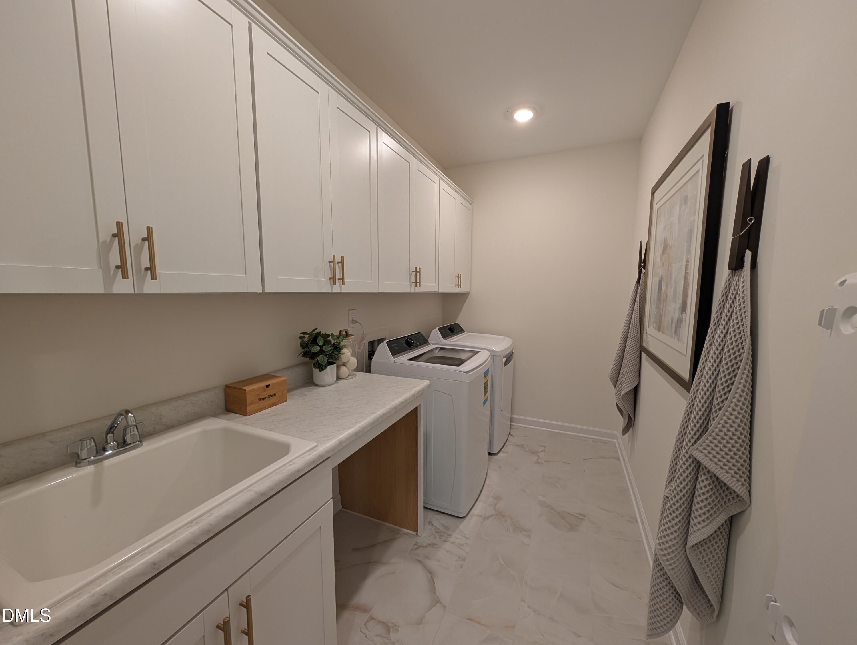 Laundry room with white cabinets, utility sink, and modern appliances in The Aspen B home at Wendell Ridge, North Carolina.