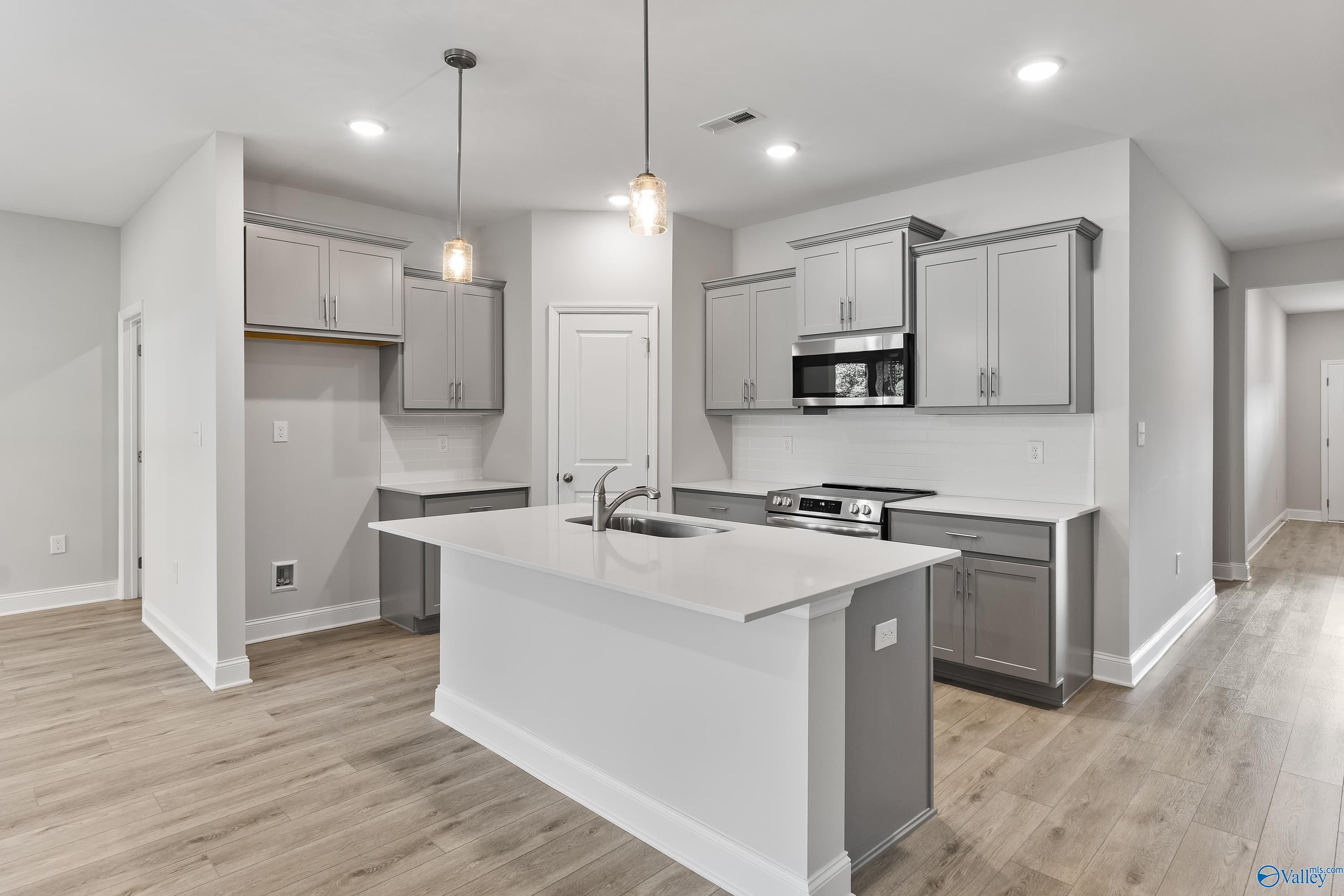 Modern kitchen with white island, gray cabinets, stainless appliances in Davidson Homes The Daphne C, Huntsville AL