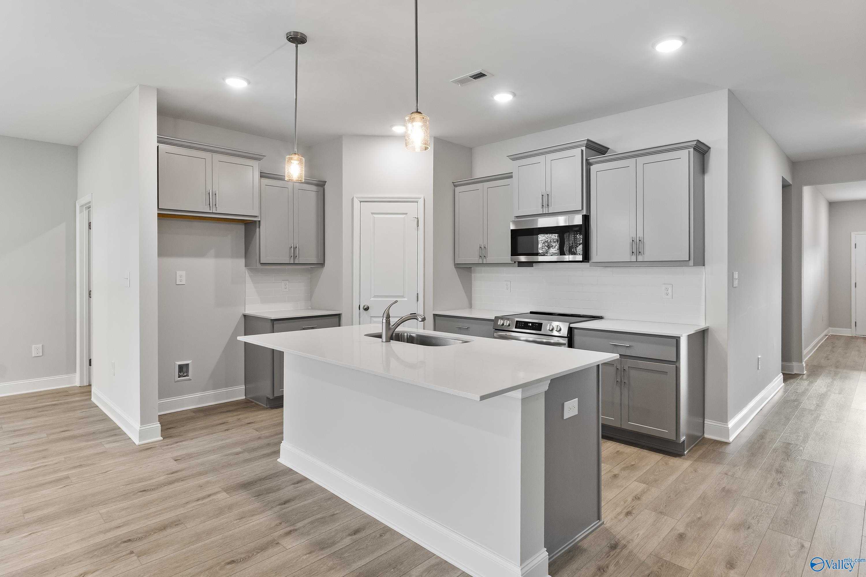 Modern kitchen with white island, gray cabinets, stainless appliances in Davidson Homes The Daphne C, Huntsville AL
