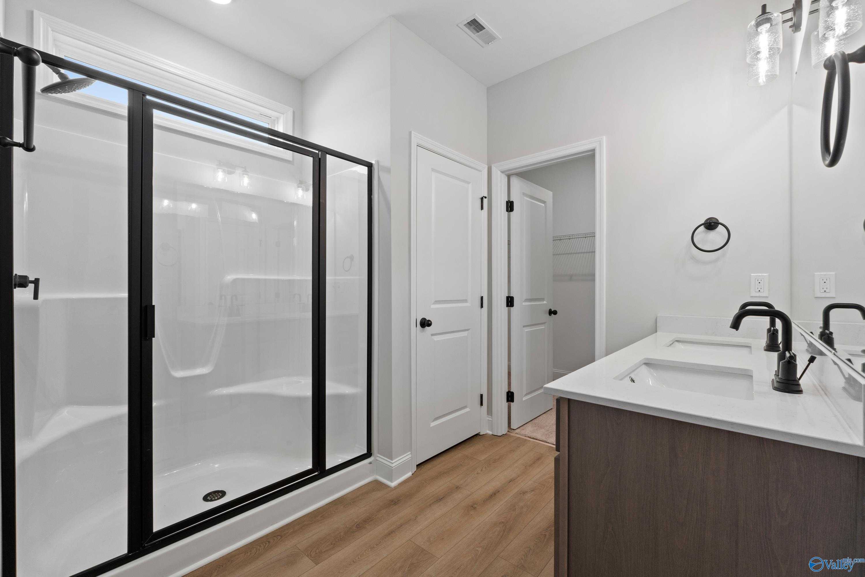 Modern master bathroom with frameless glass shower and double quartz vanity in Davidson Homes The Franklin C, Hazel Green, Alabama