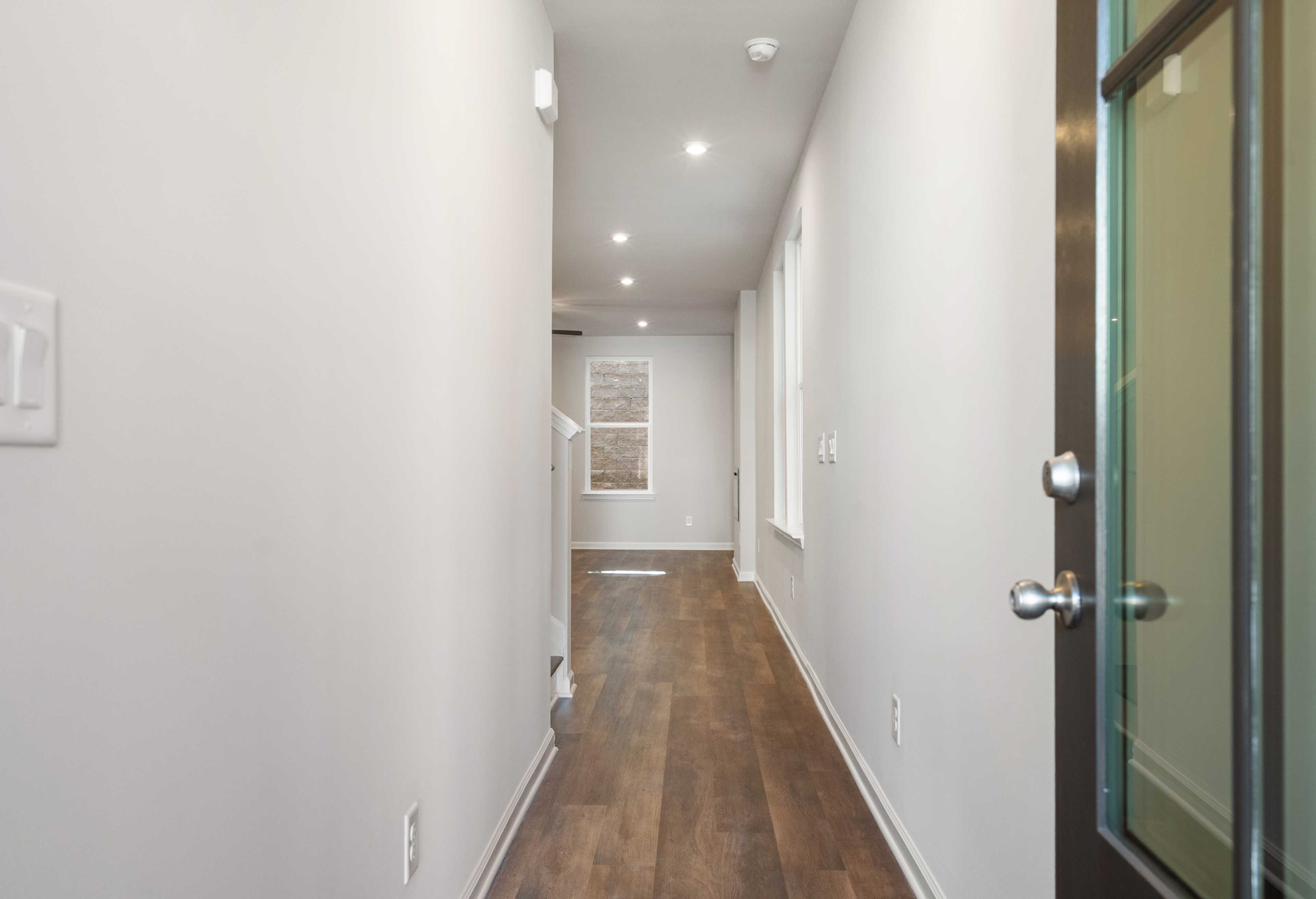 Spacious hallway in The Cary B home with hardwood floors, gray walls, and recessed lighting, Davidson Homes design