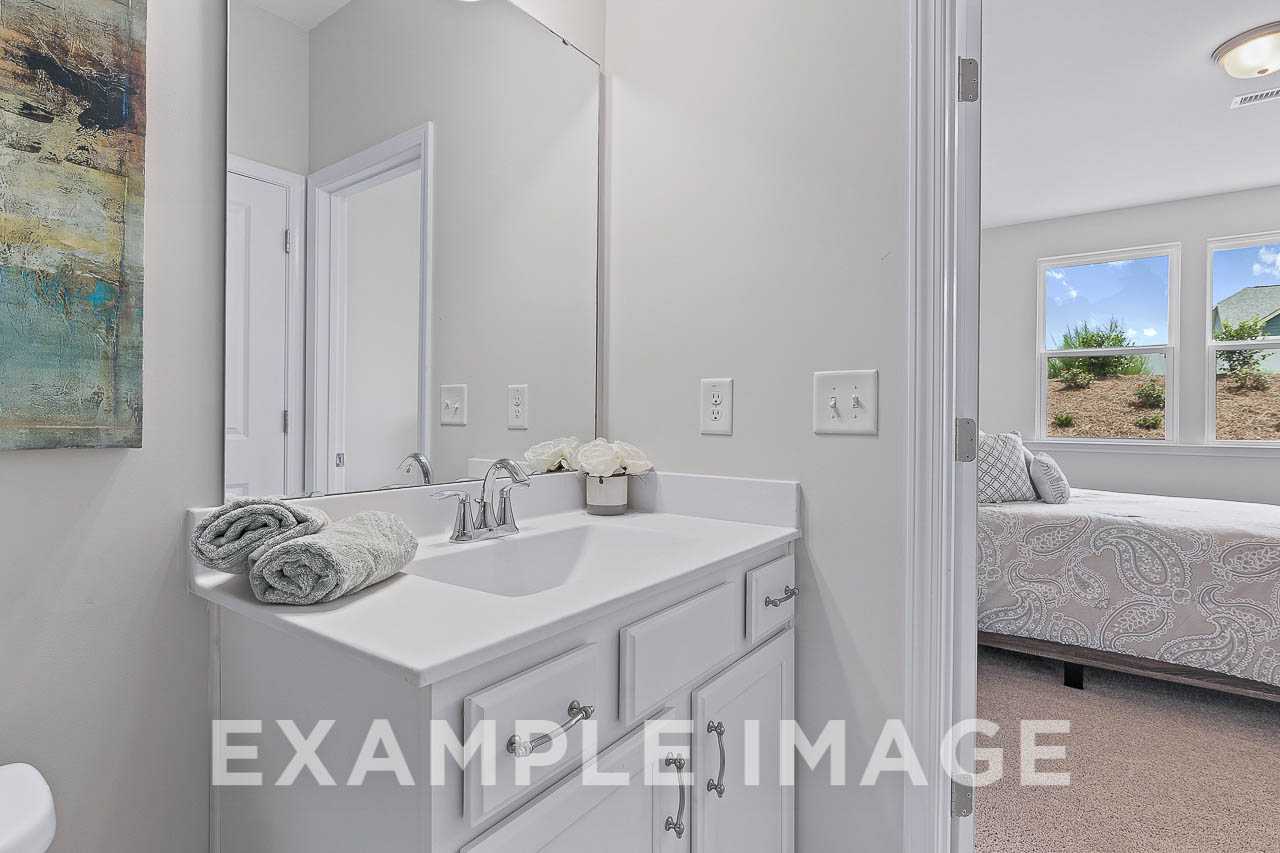Master bathroom in The Willow C featuring white vanity sink, towels, and open view to adjacent bedroom