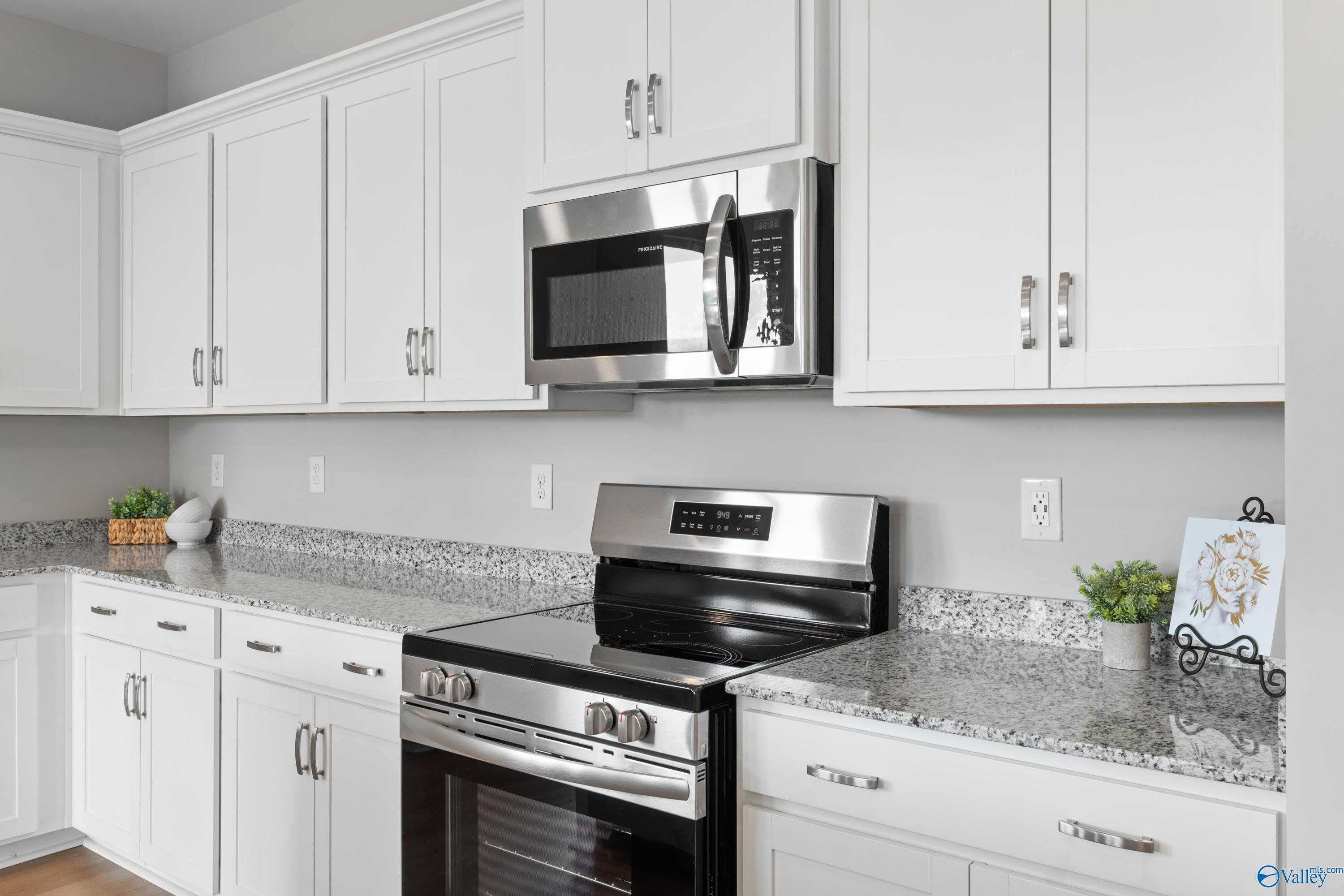 Modern kitchen with white shaker cabinets, stainless steel microwave and oven, granite countertops in The Aurora floor plan by Davidson Homes, Fayetteville, TN