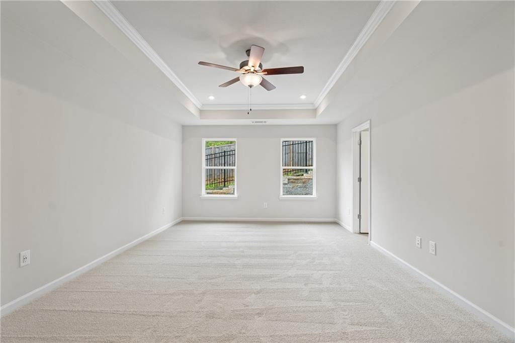 Spacious secondary bedroom with tray ceiling, ceiling fan, and large windows in Davidson Homes The Marion B, Kennesaw, Georgia