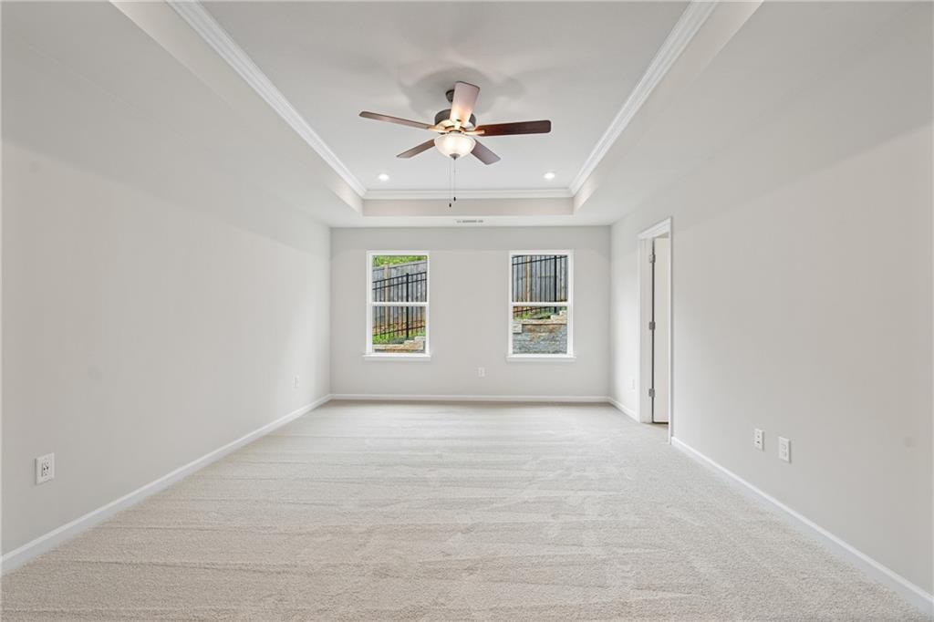 Spacious secondary bedroom with tray ceiling, ceiling fan, and large windows in Davidson Homes The Marion B, Kennesaw, Georgia